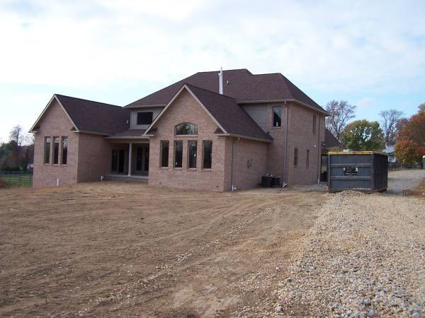 A large brick house is sitting in the middle of a dirt field