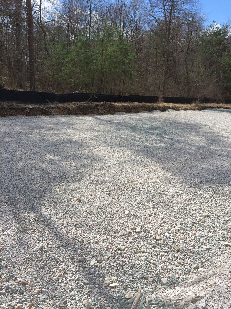 A gravel road in the middle of a forest with trees in the background.