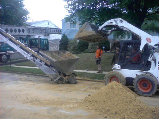 A bulldozer is loading dirt into a conveyor belt.