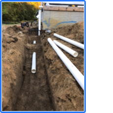 A bunch of white pipes are laying in the dirt