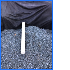 A white pole is sitting in a pile of gravel