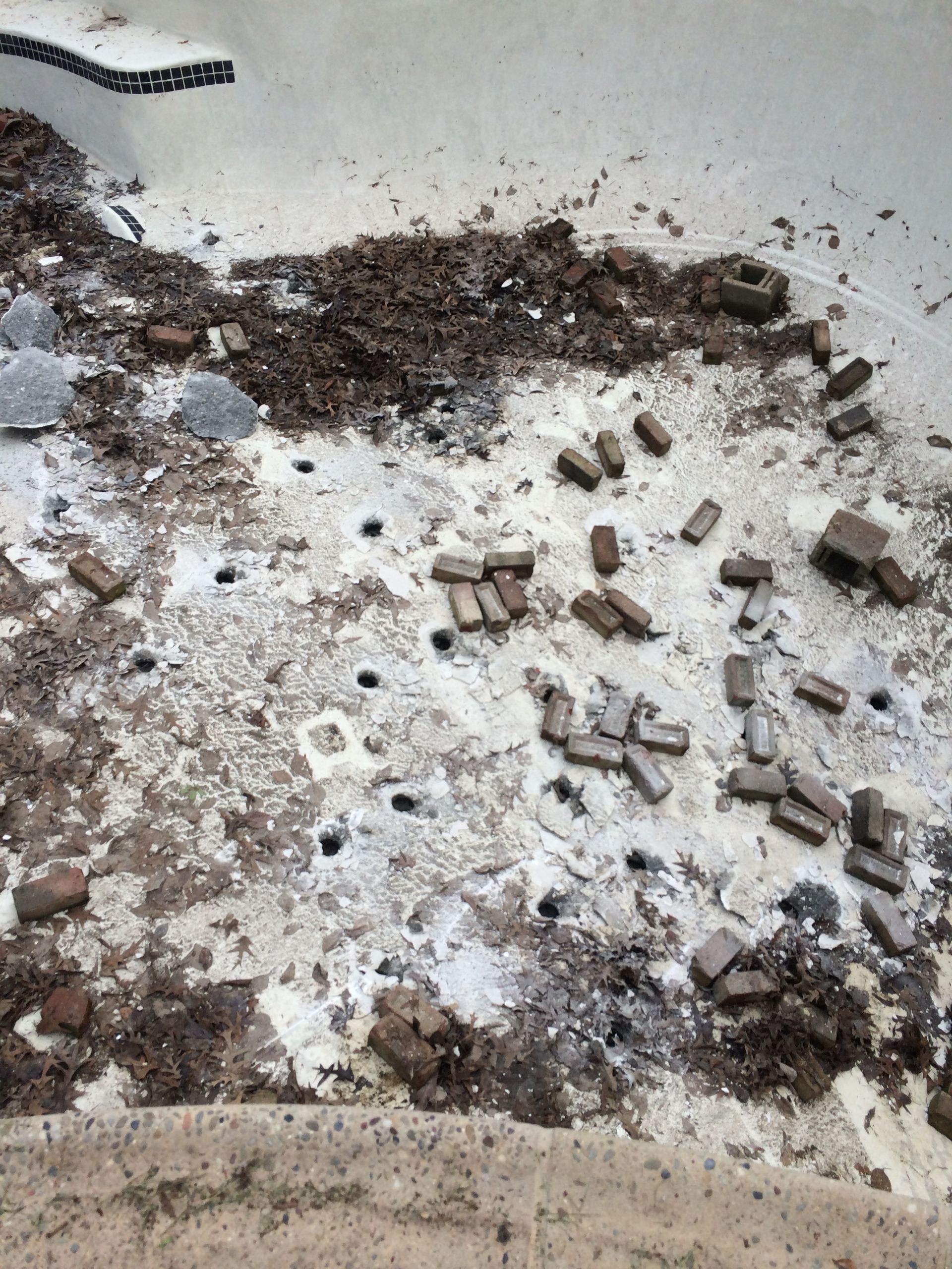 A pool with a lot of dirt and bricks on it