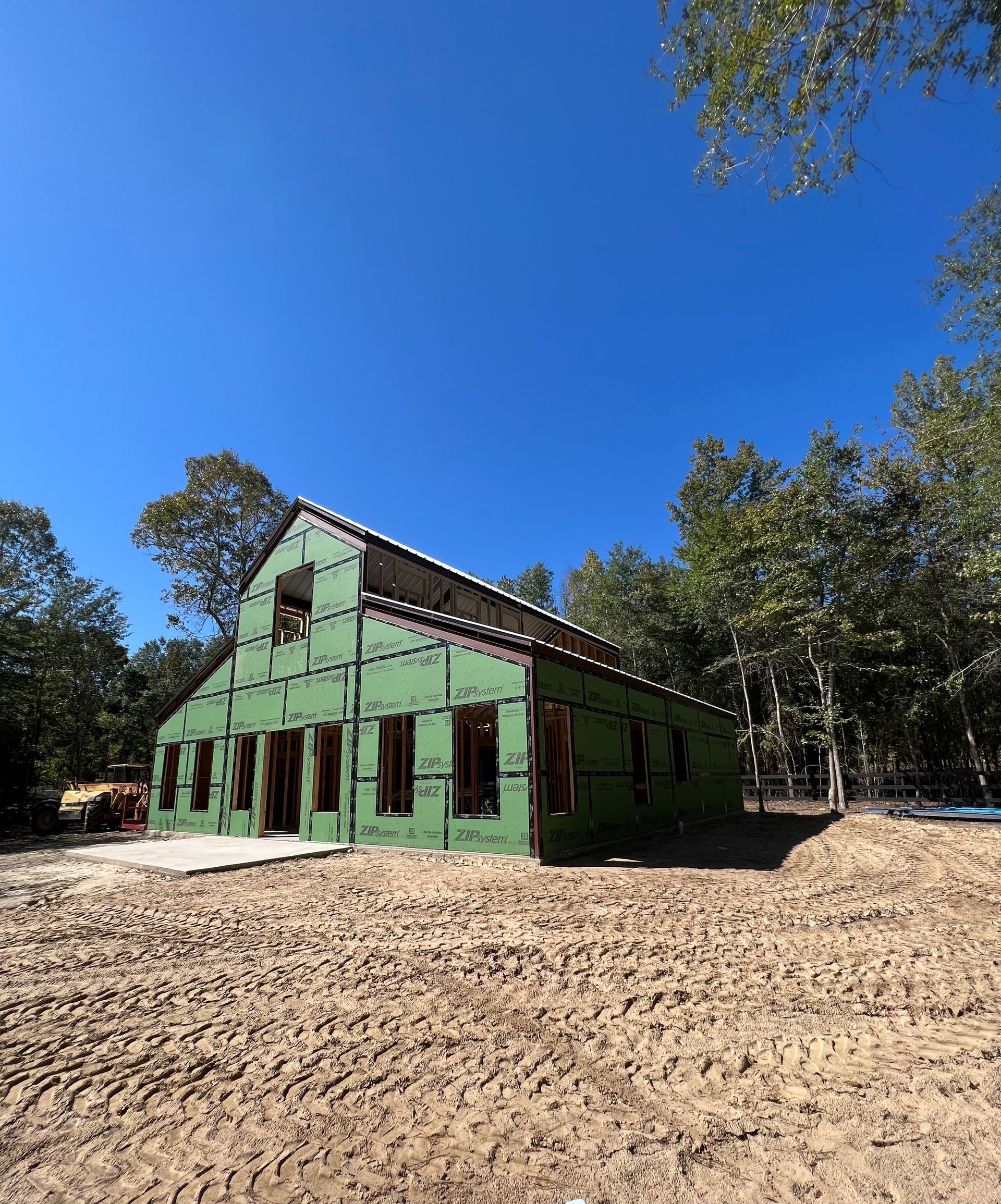 A large metal structure is being built on a dirt road.