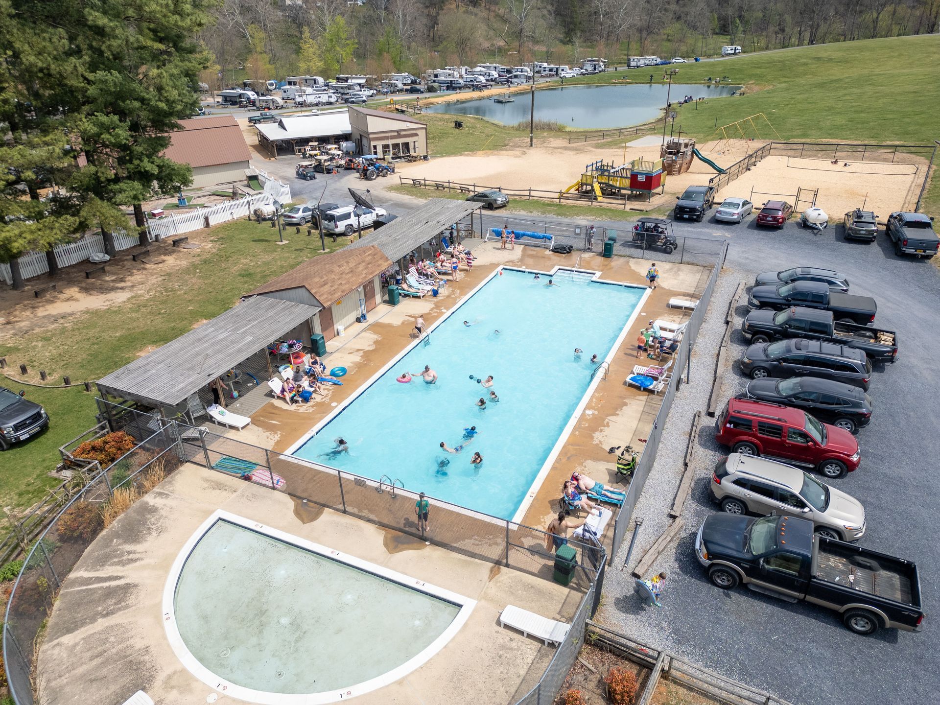 An aerial view of a swimming pool with cars parked around it.