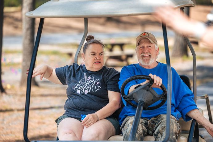 A man and a woman are sitting in a golf cart.