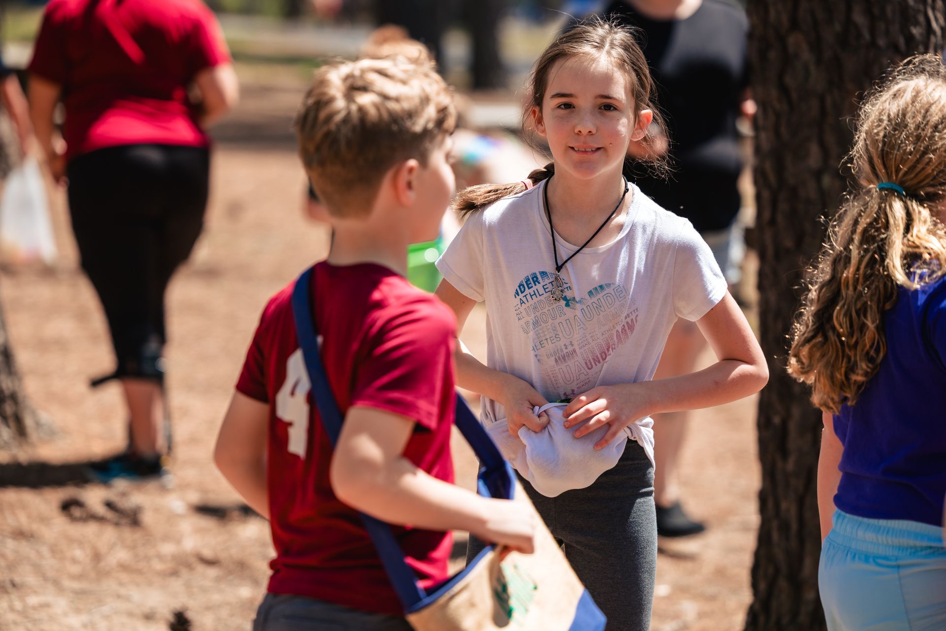A boy and a girl are standing next to each other in a park.