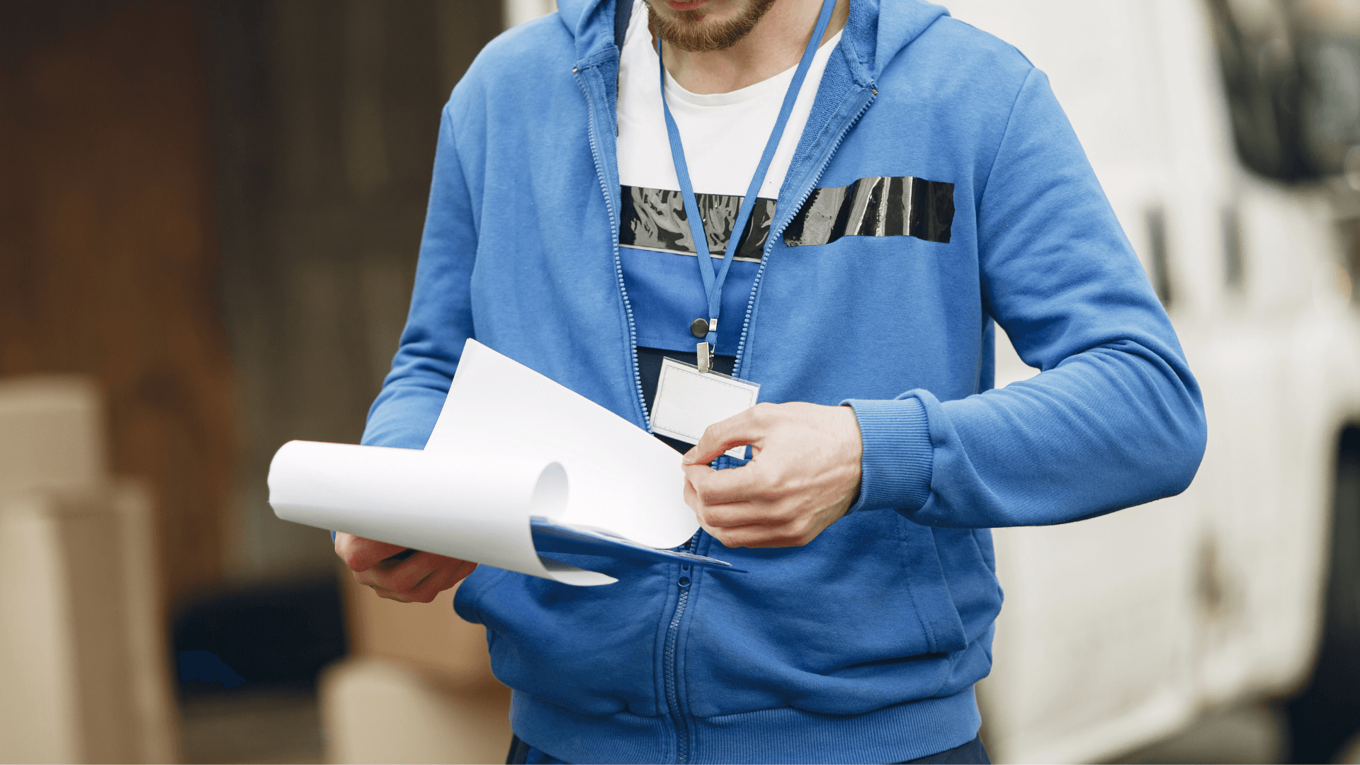 A man in a blue hoodie is holding a piece of paper.