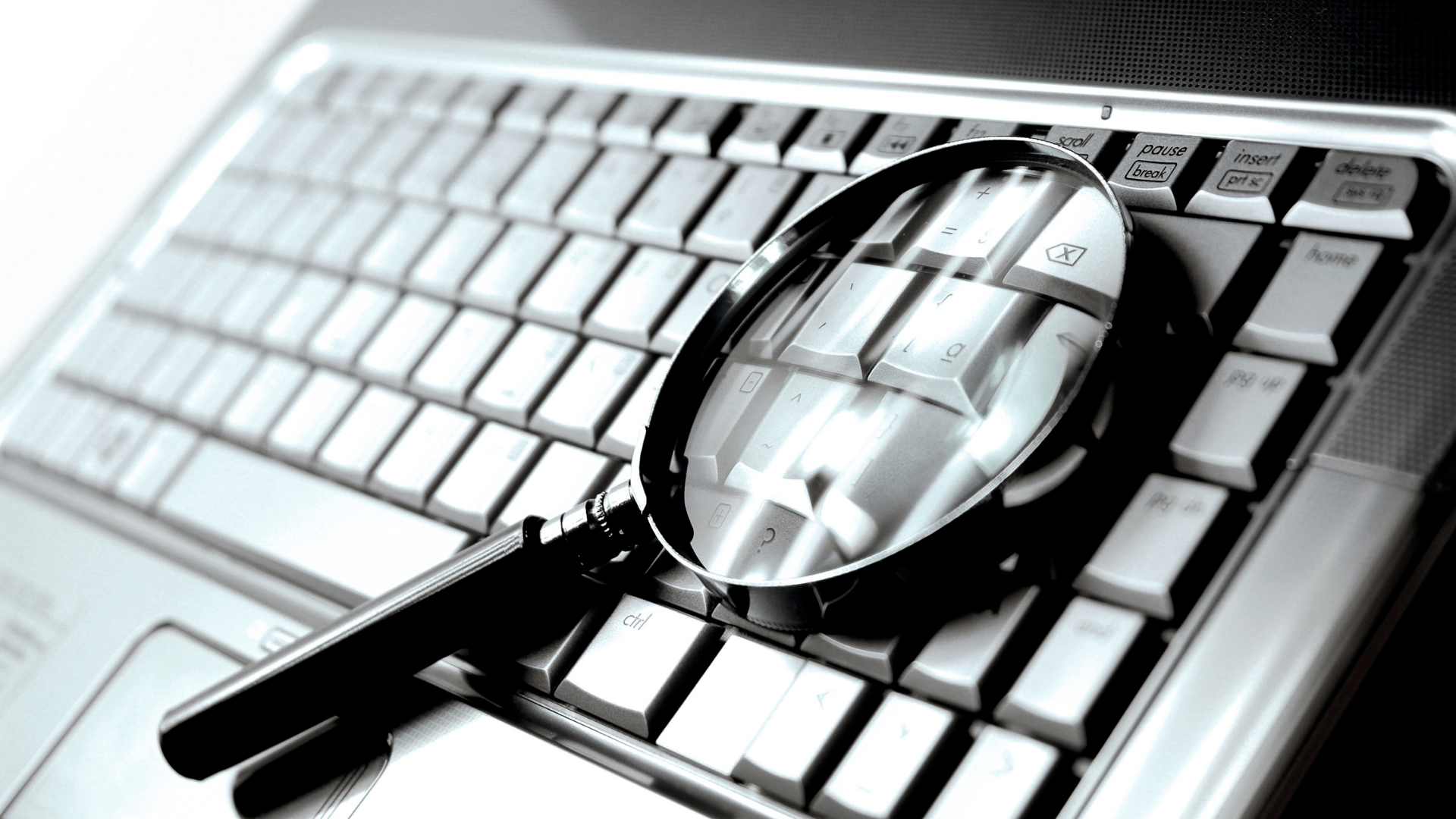 A magnifying glass is sitting on top of a laptop keyboard