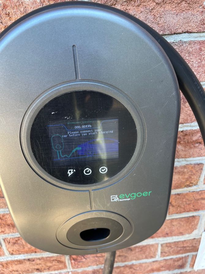 EV charger mounted on a brick wall, with a screen displaying information.