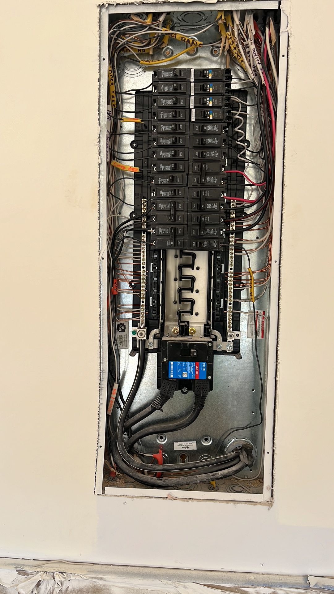 Open electrical panel with numerous wires and circuit breakers.