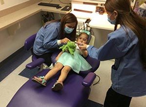 Dentists Talking To A Child With A Stuffed Toy — Child Dental Care In Mcallen, TX