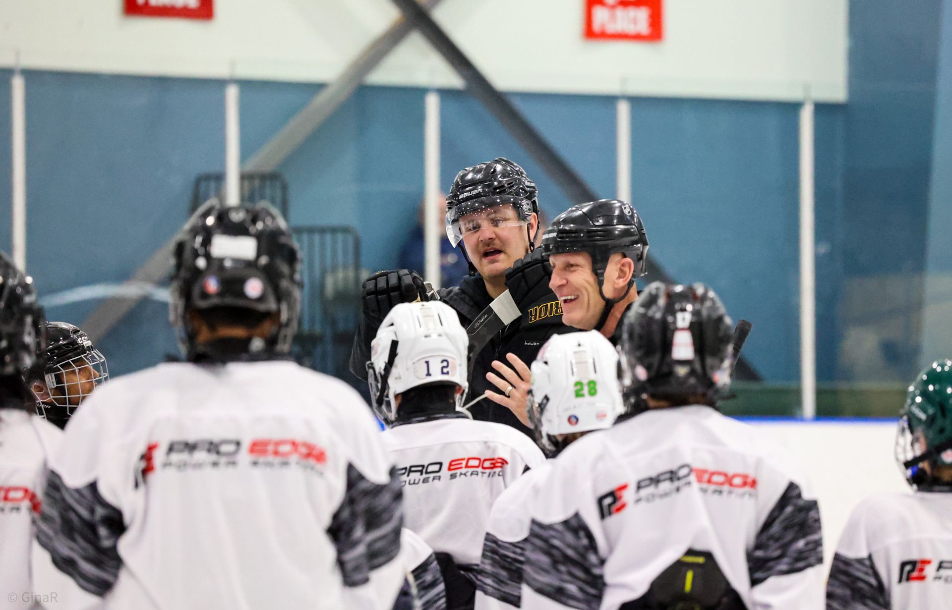 A group of hockey players are standing in a huddle on the ice.