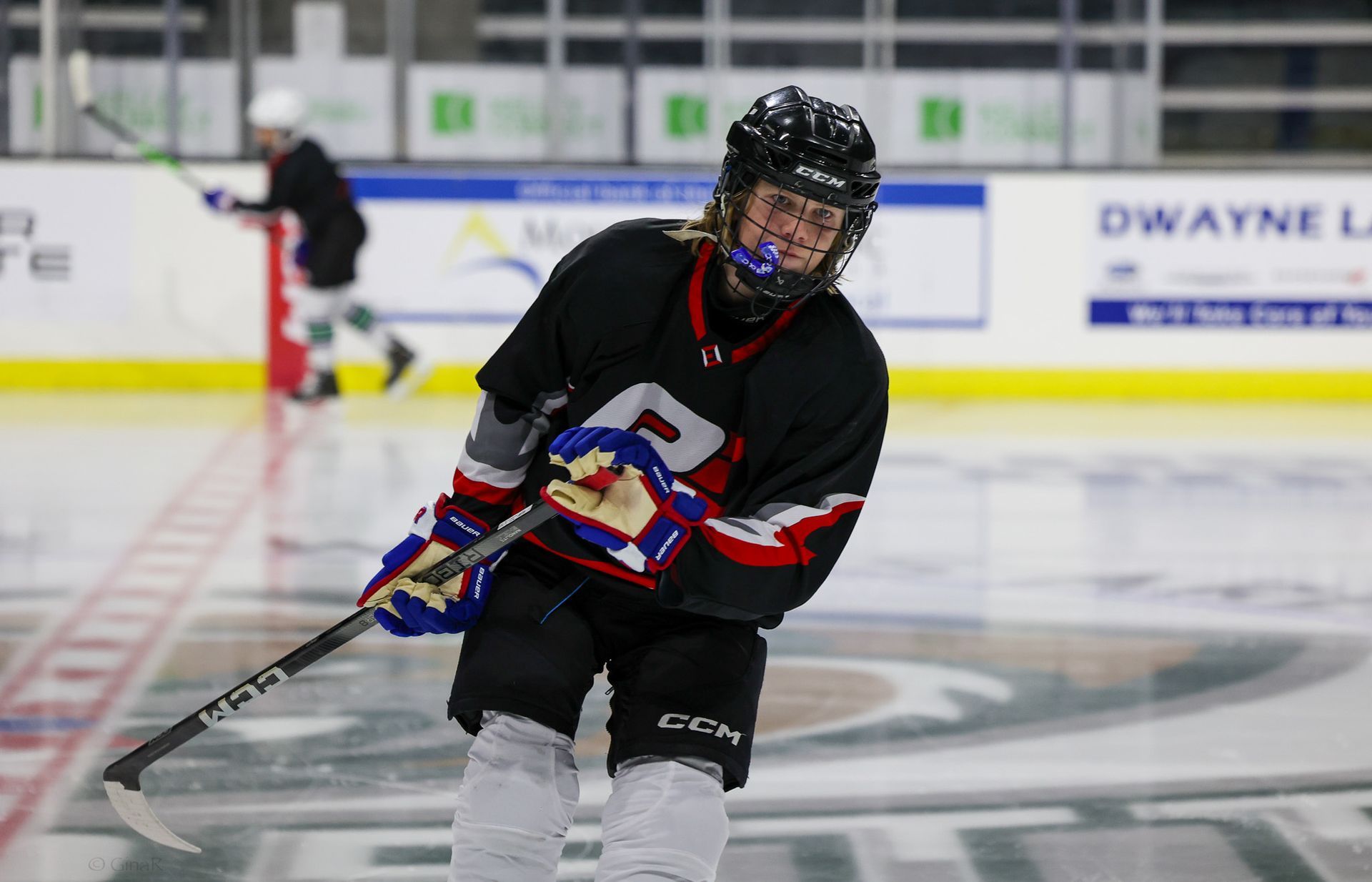 A hockey player is holding a hockey stick on the ice.