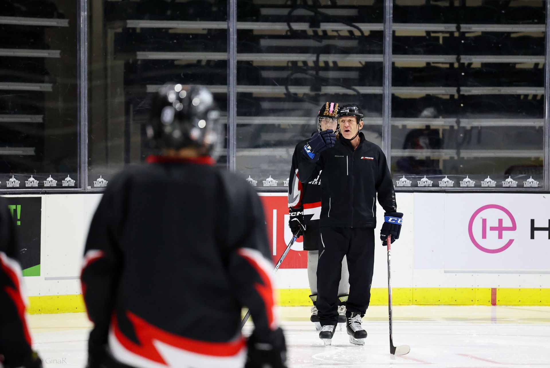 A man is standing on a hockey rink holding a hockey stick.