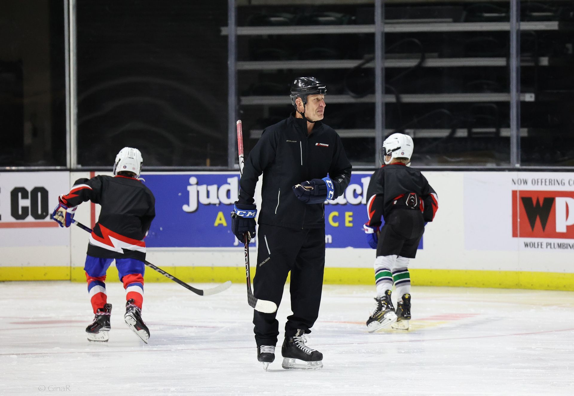 A man is standing on a ice rink with hockey players