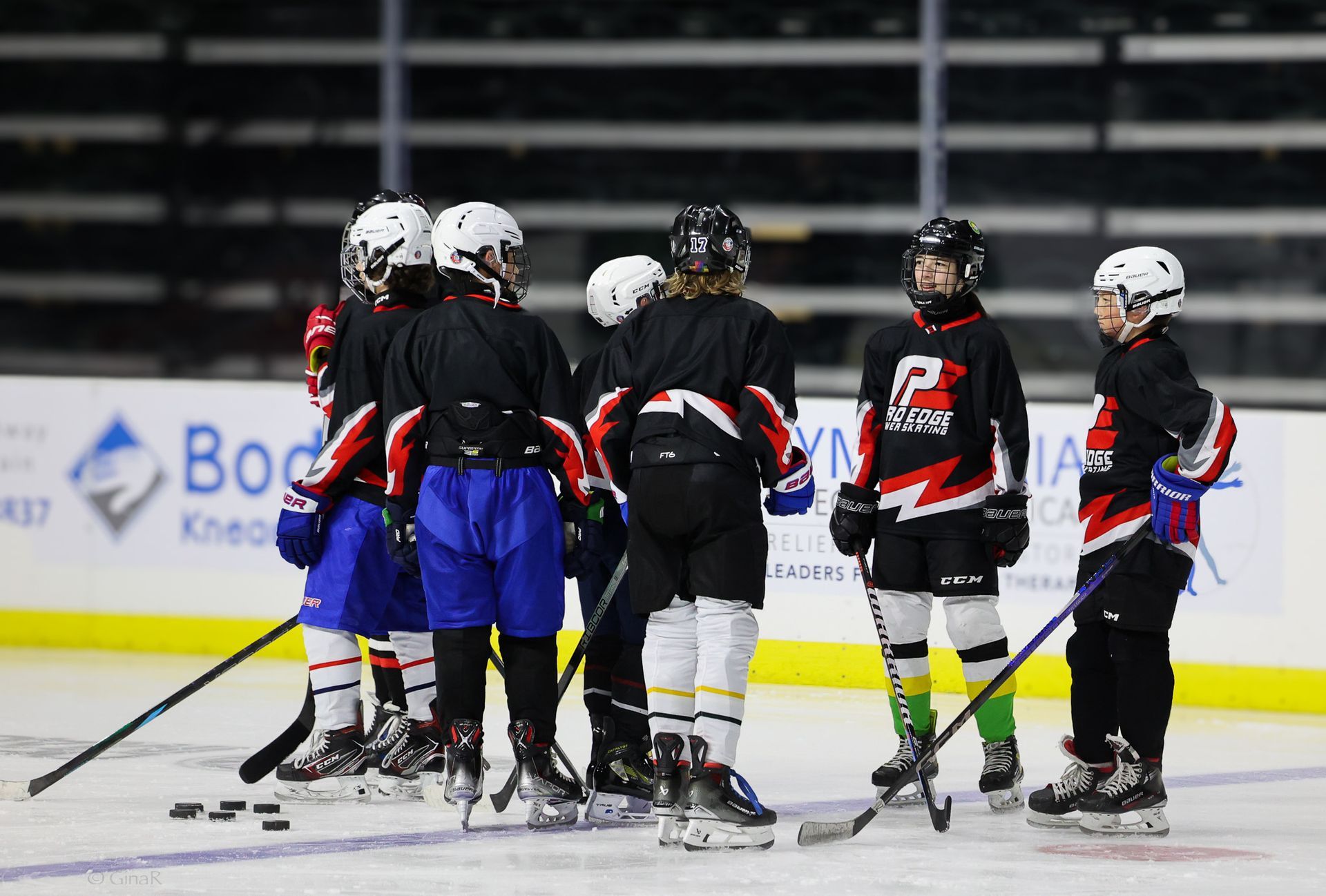 A group of young hockey players are huddled together on the ice.