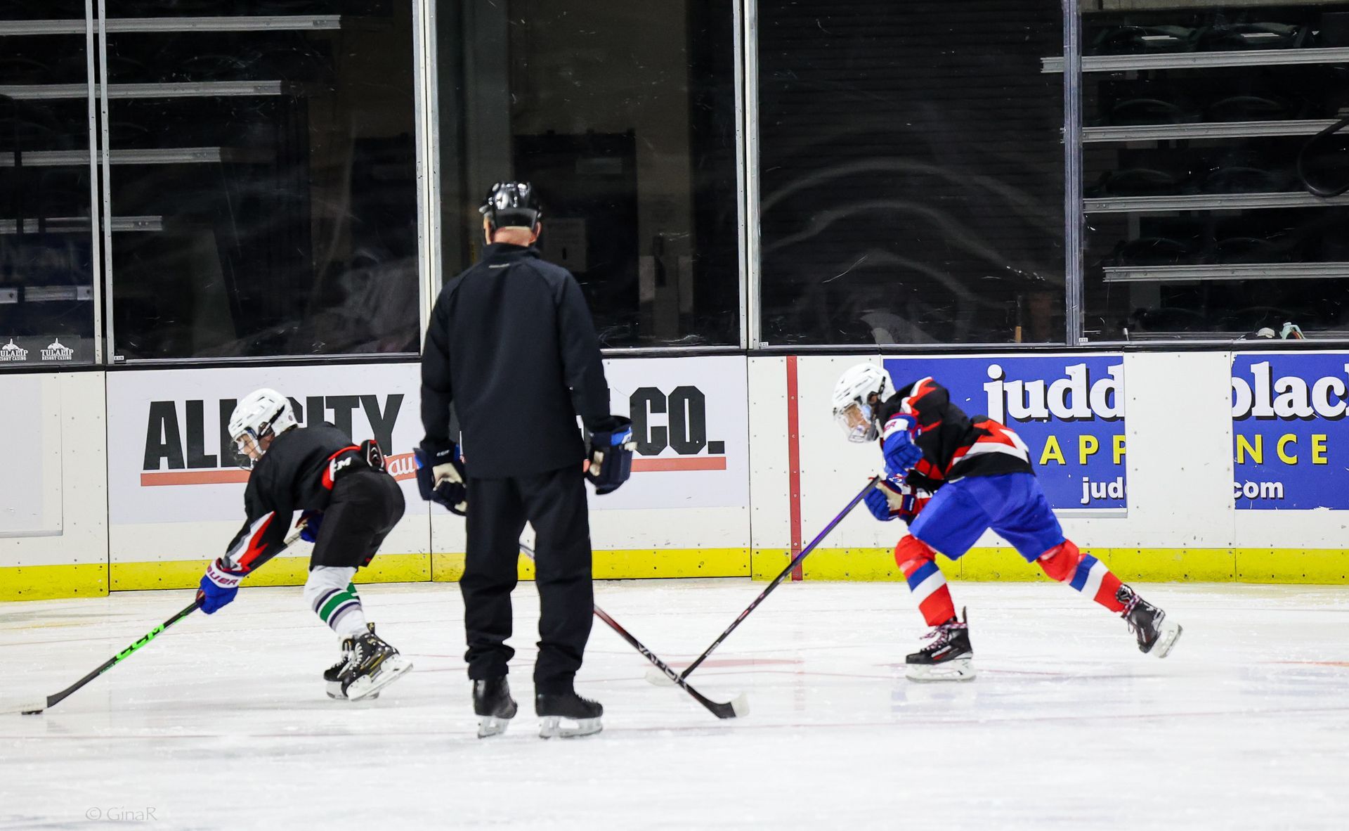 A hockey game is being played on a rink with a sign that says all city co.
