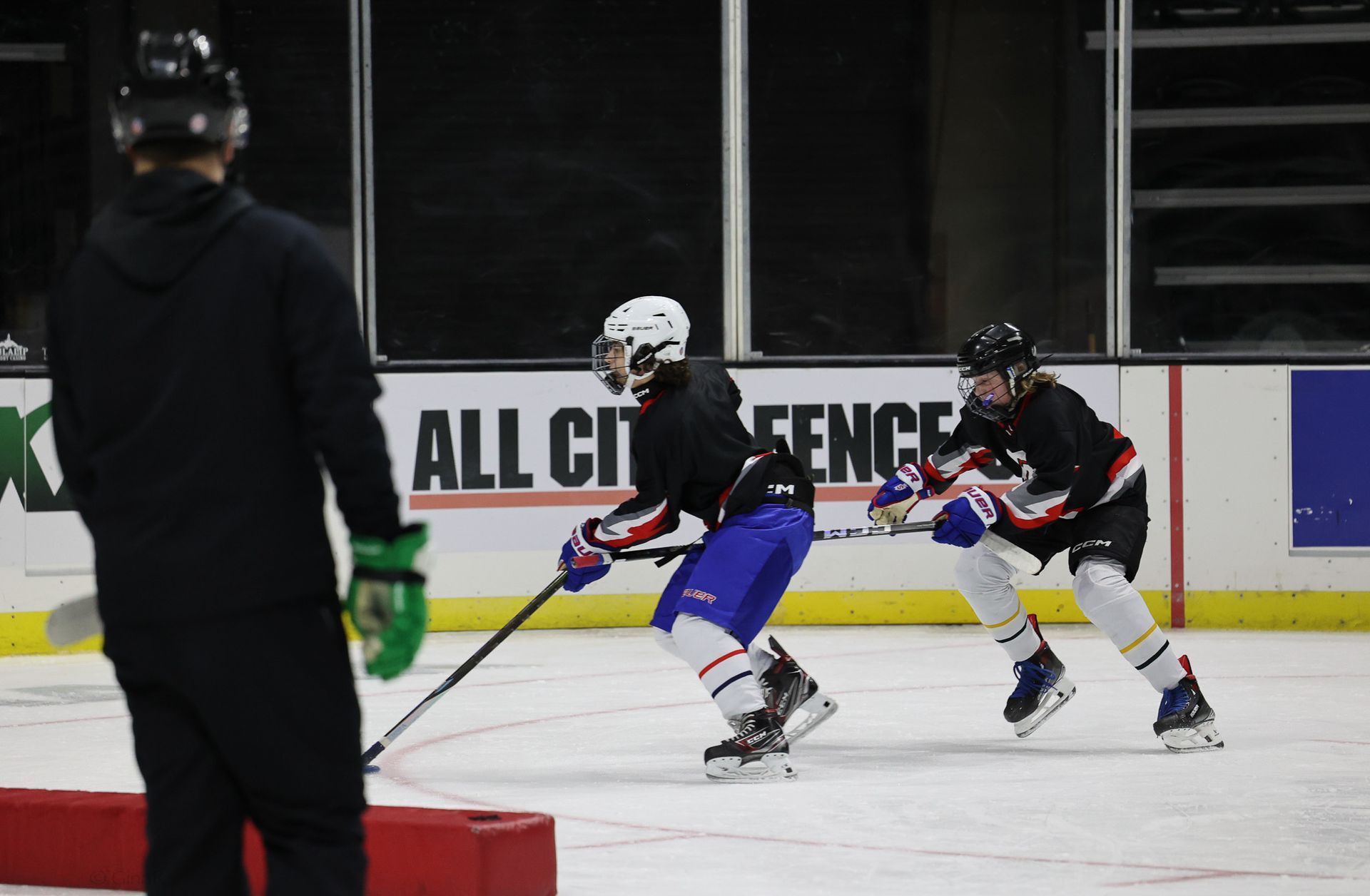 A hockey game is being played in front of a sign that says all city fence