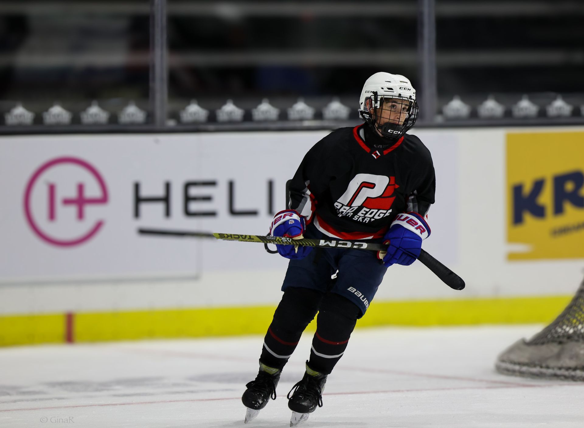 A hockey player is skating on the ice in front of an advertisement for helix