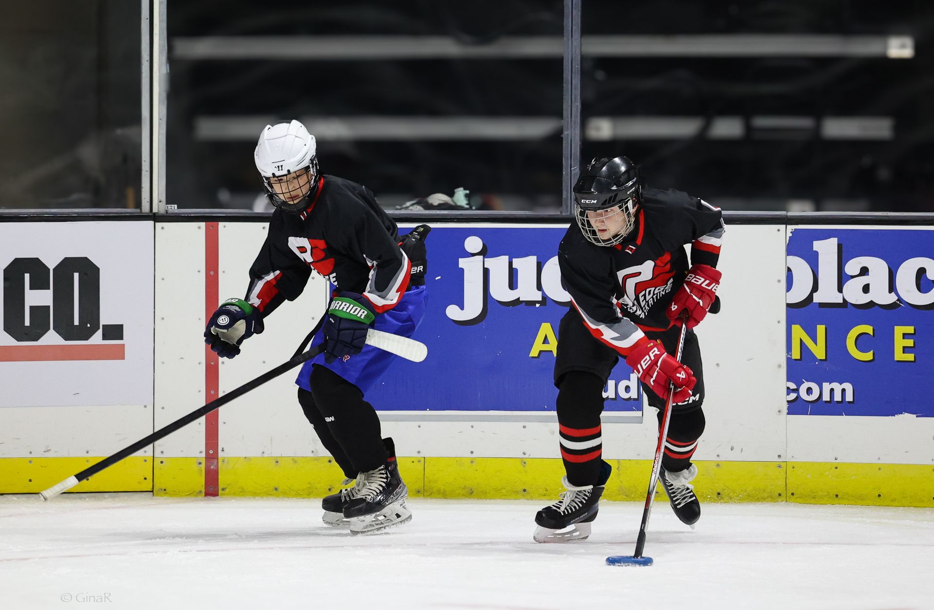 Two young boys are playing ice hockey on a rink.