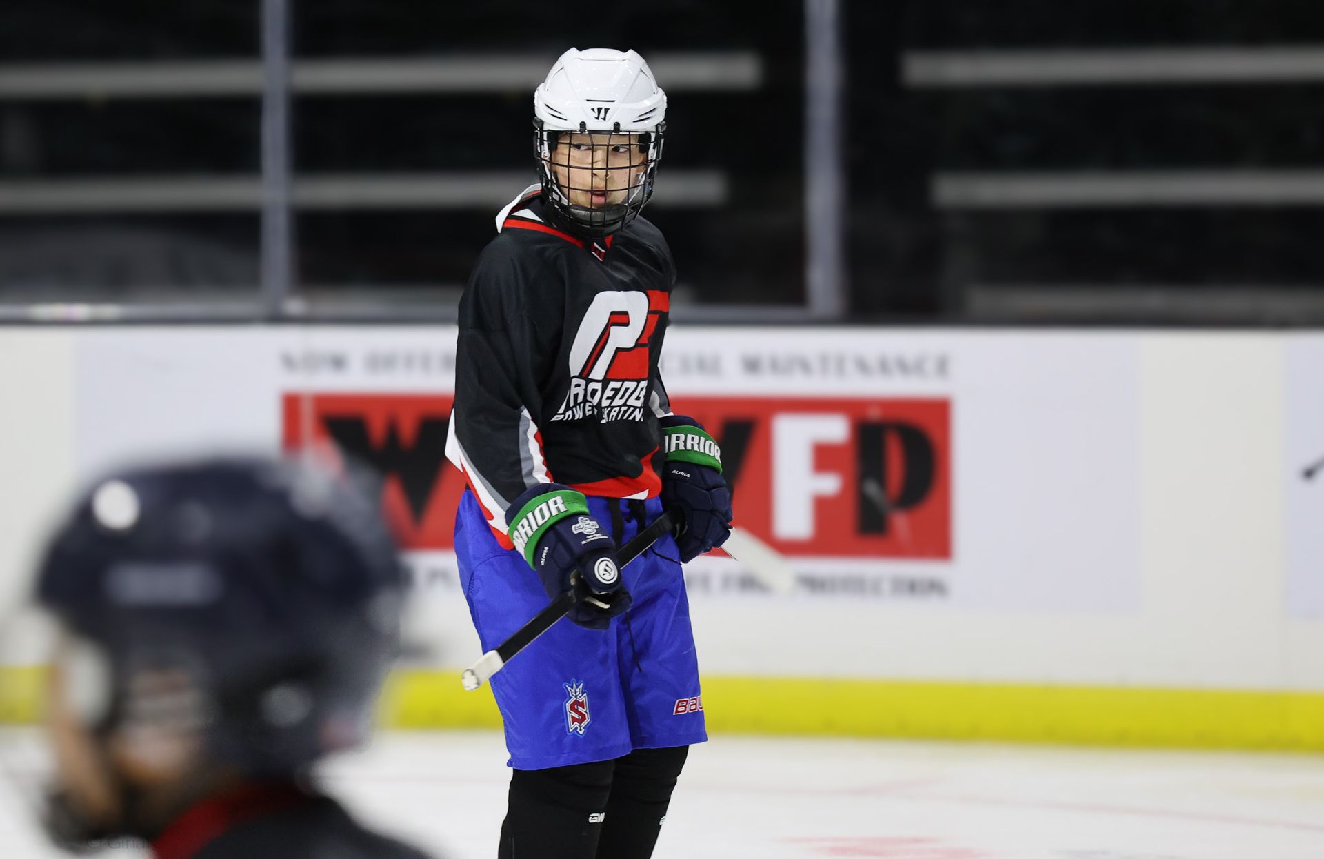 A hockey player is standing on the ice in front of a sign that says fp
