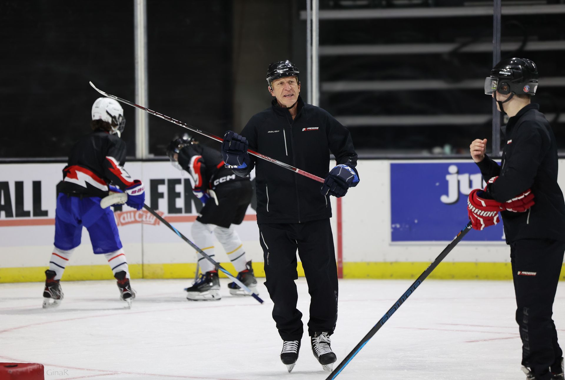A man is holding a hockey stick in front of a sign that says all fen