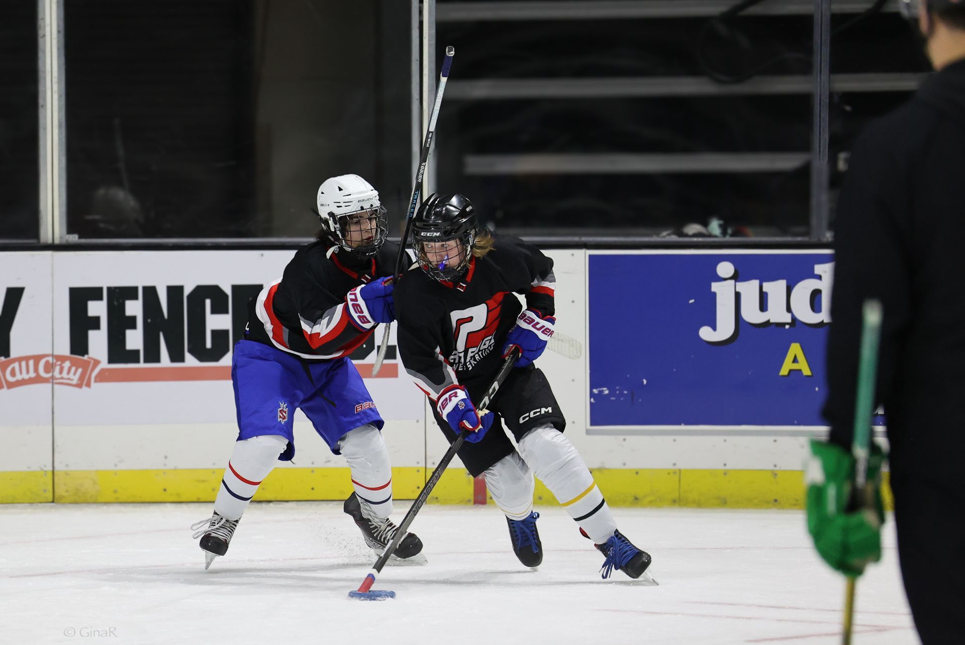 A hockey game is being played in front of a sign that says jud a