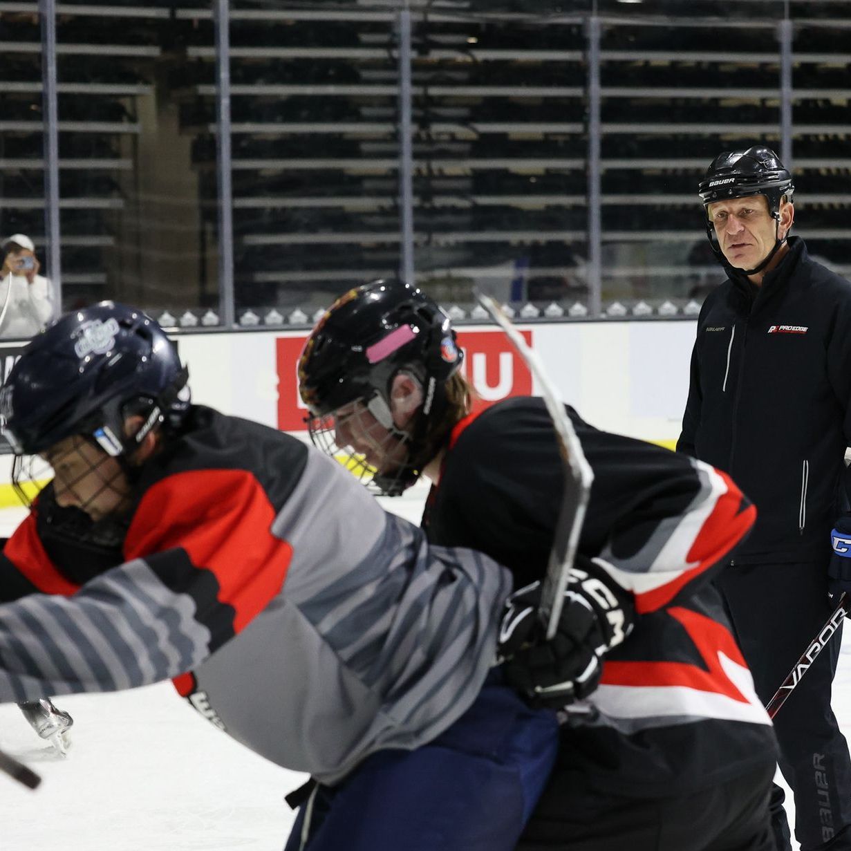A hockey game is being played with the letter u on the ice