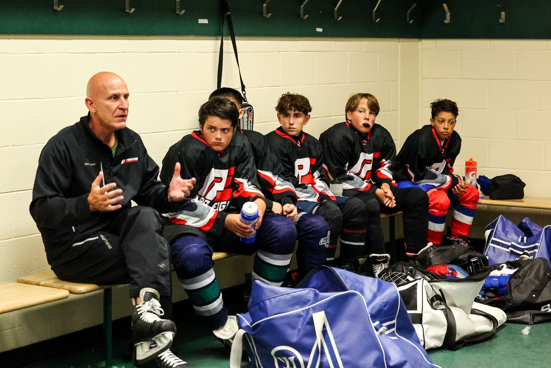 A group of hockey players are sitting on a bench in a locker room.