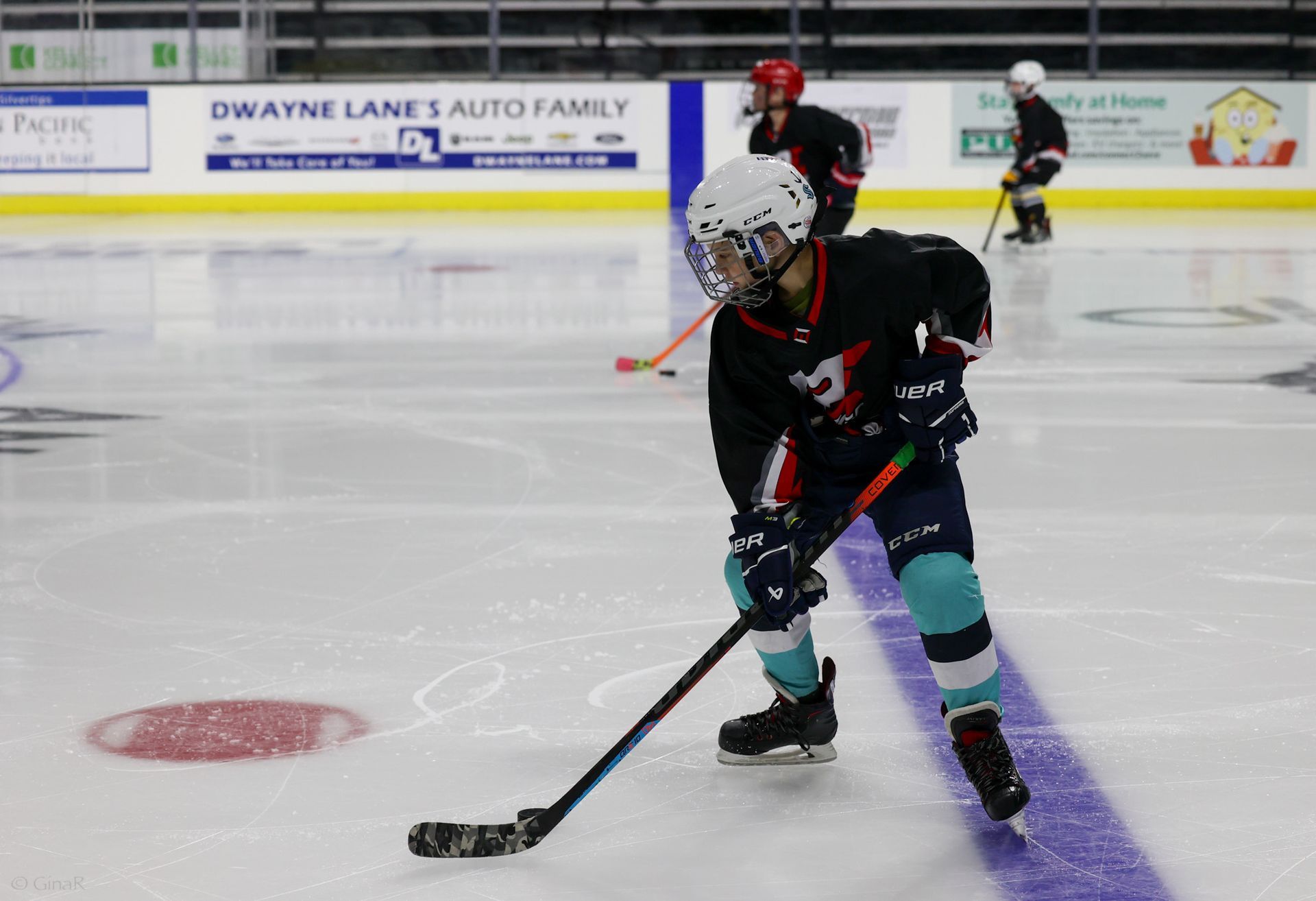 A hockey player is skating on the ice with a puck.