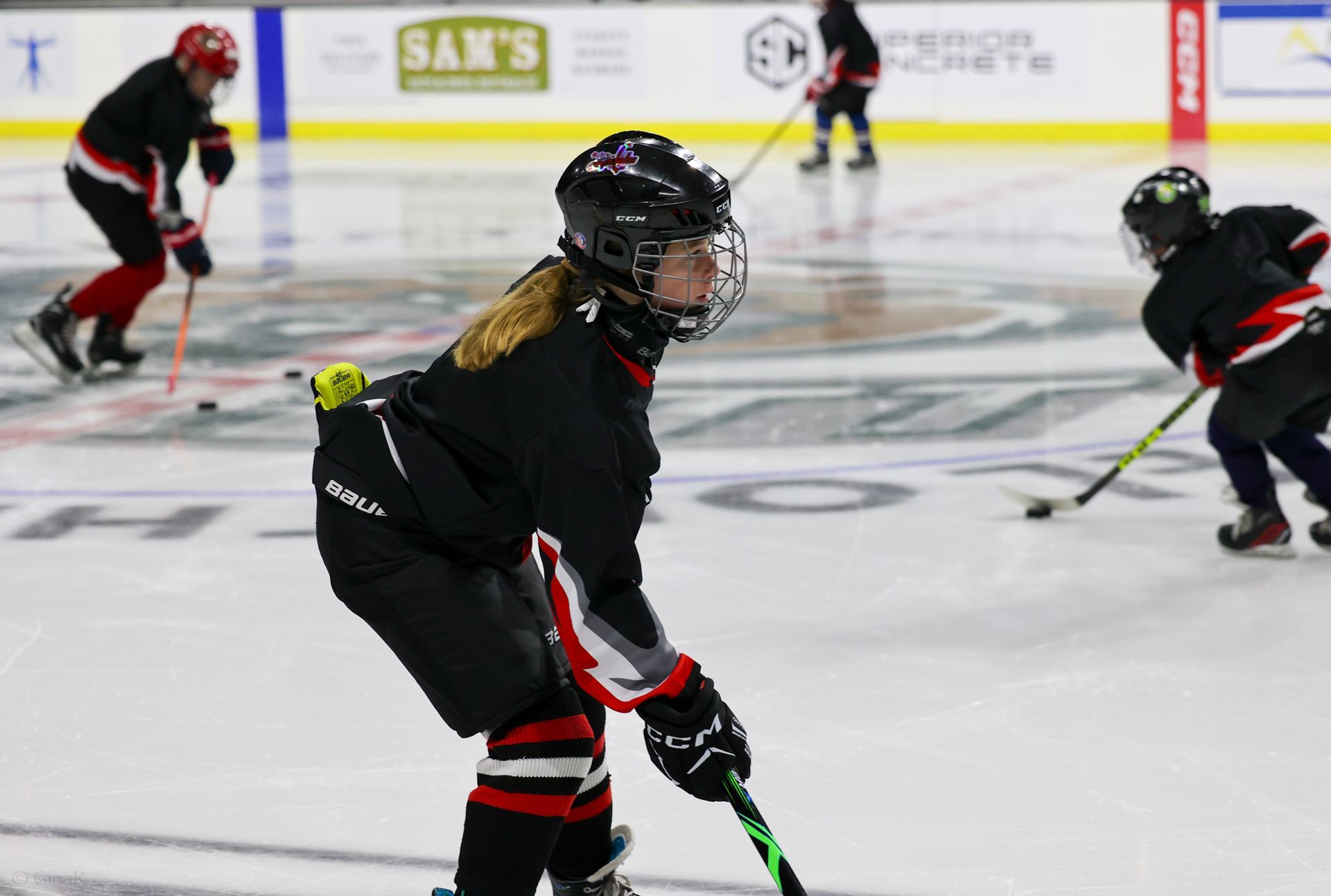 A girl is holding a hockey stick while playing hockey on the ice.