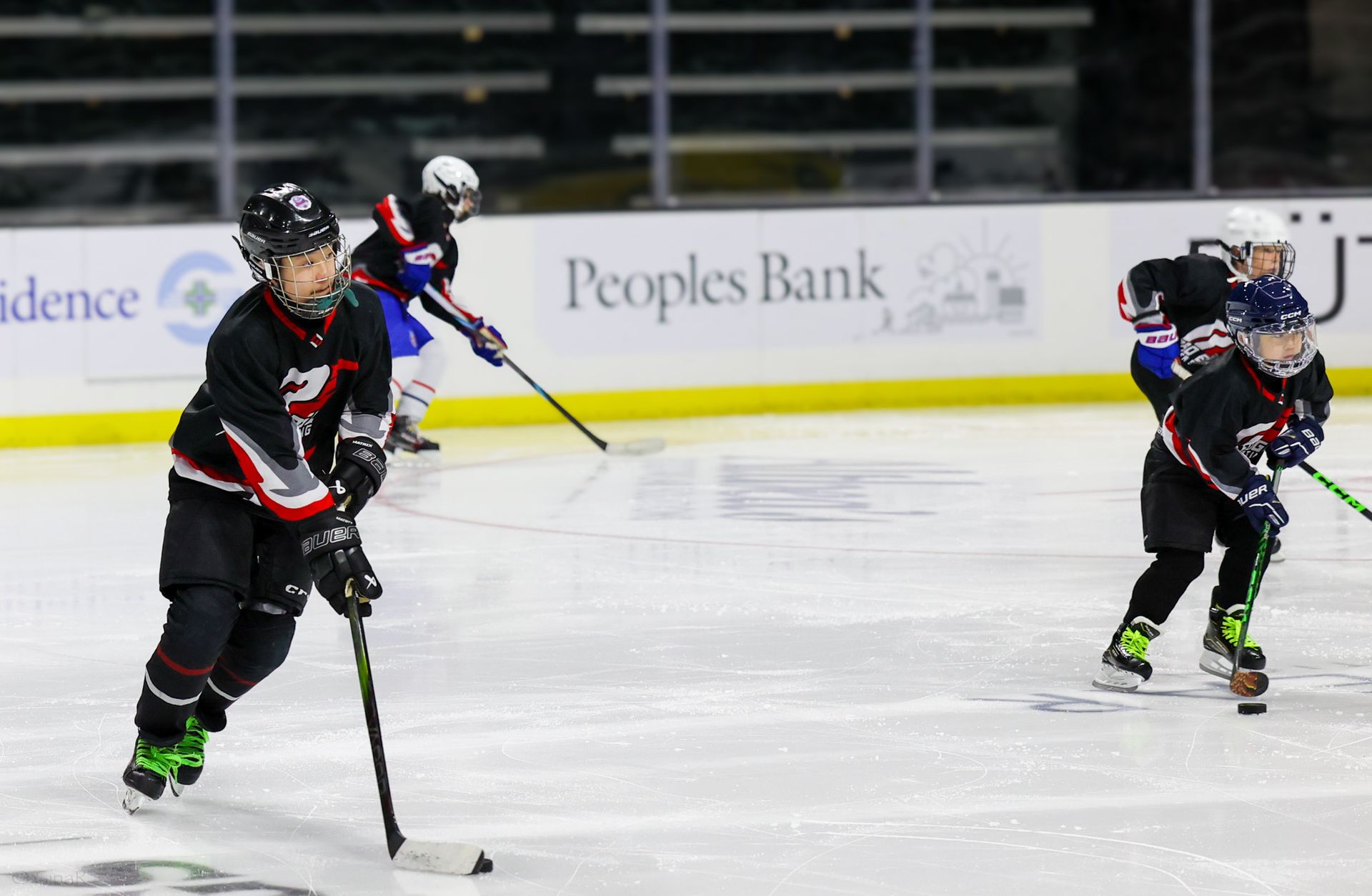 A hockey game is being played in front of a peoples bank sign.
