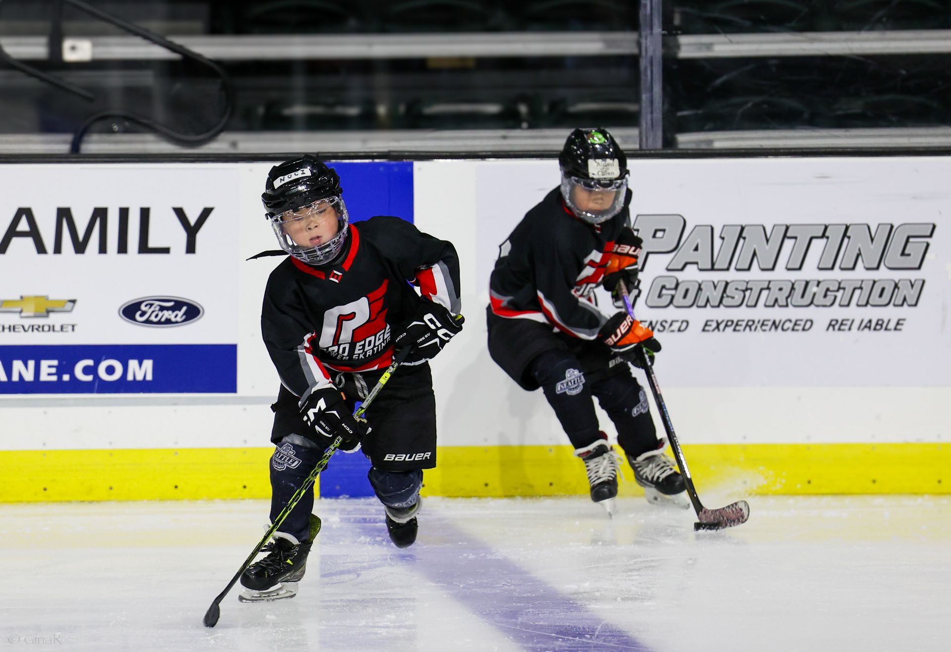 Two hockey players are on the ice in front of a sign that says amily