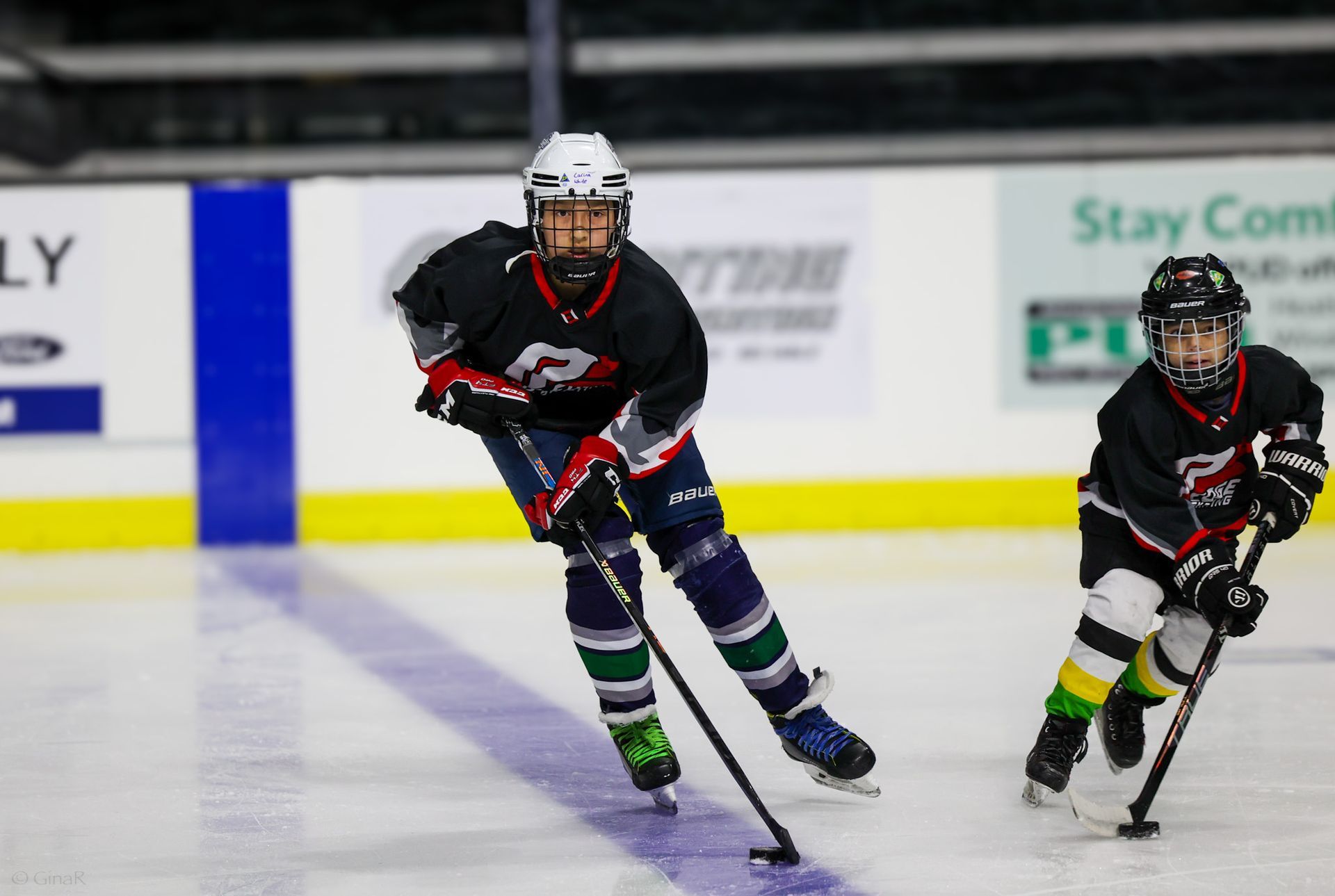 Two young boys are playing ice hockey on a rink.