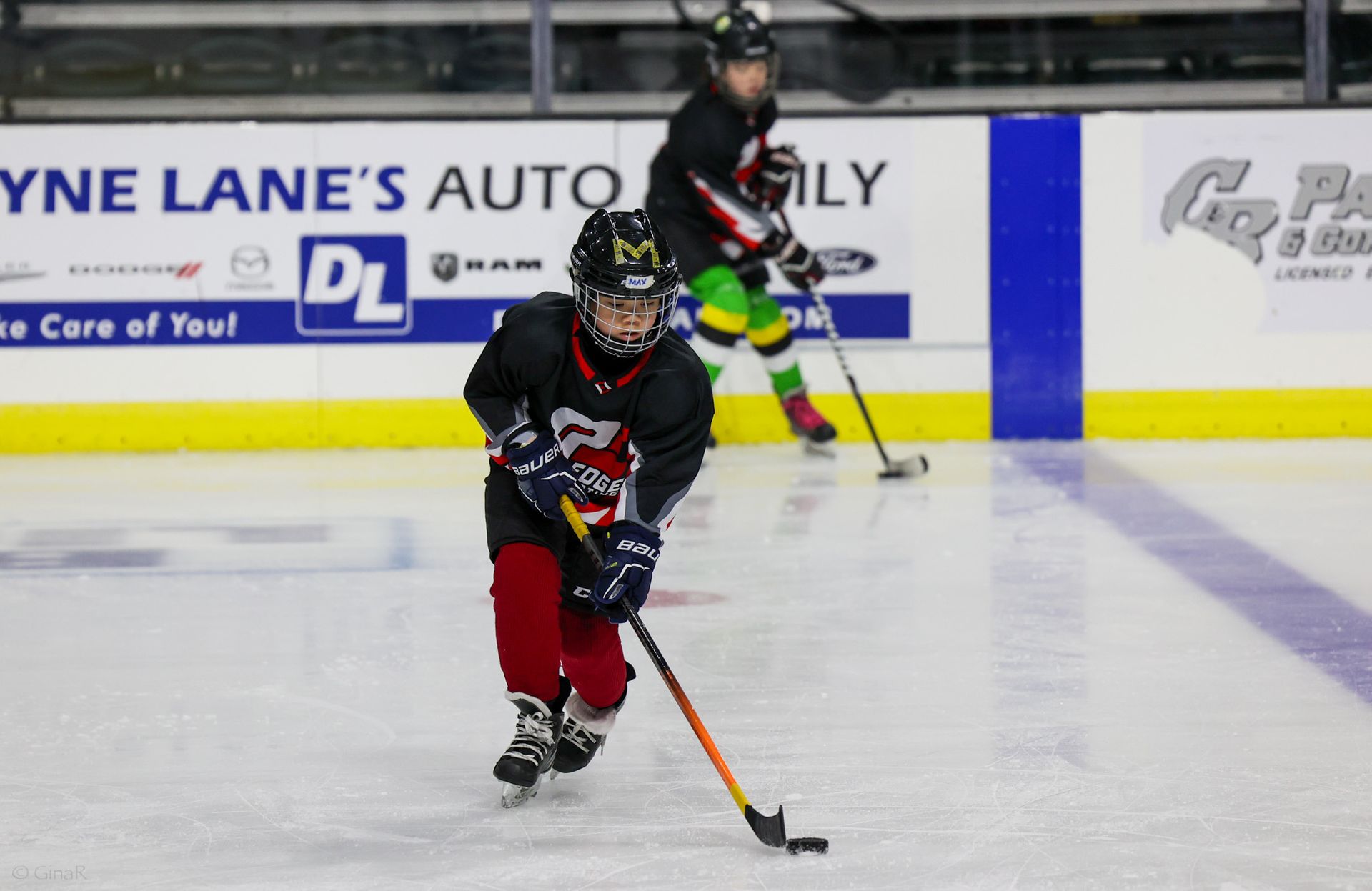 A hockey game is being played in front of a sign for dyne lane 's auto