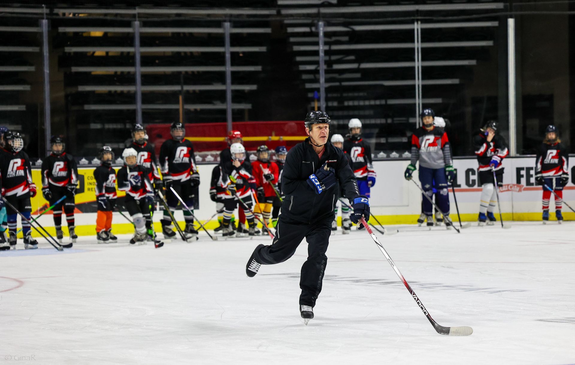 A man is holding a hockey stick on a ice rink.