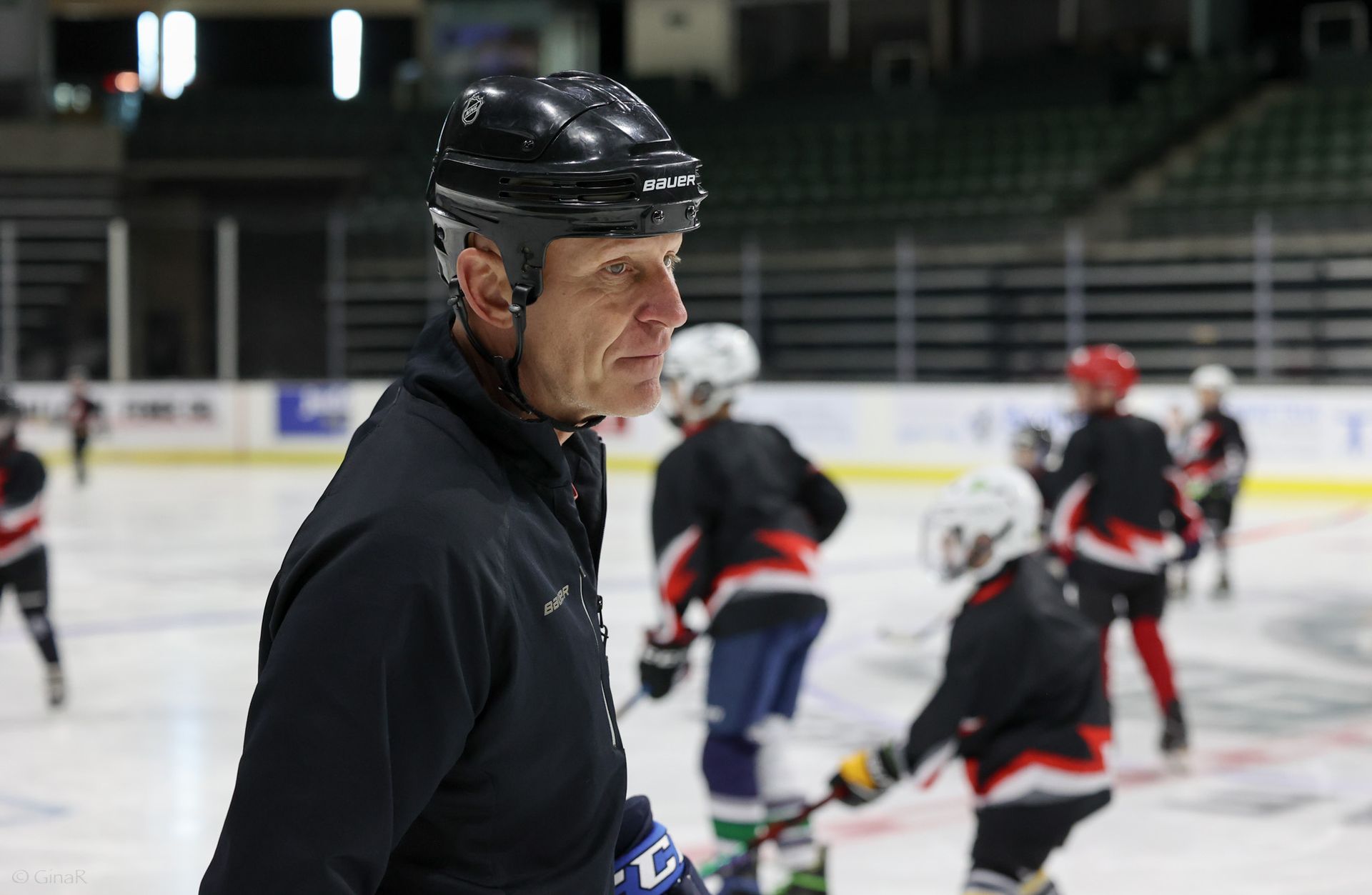 A man wearing a helmet is standing on a hockey rink.