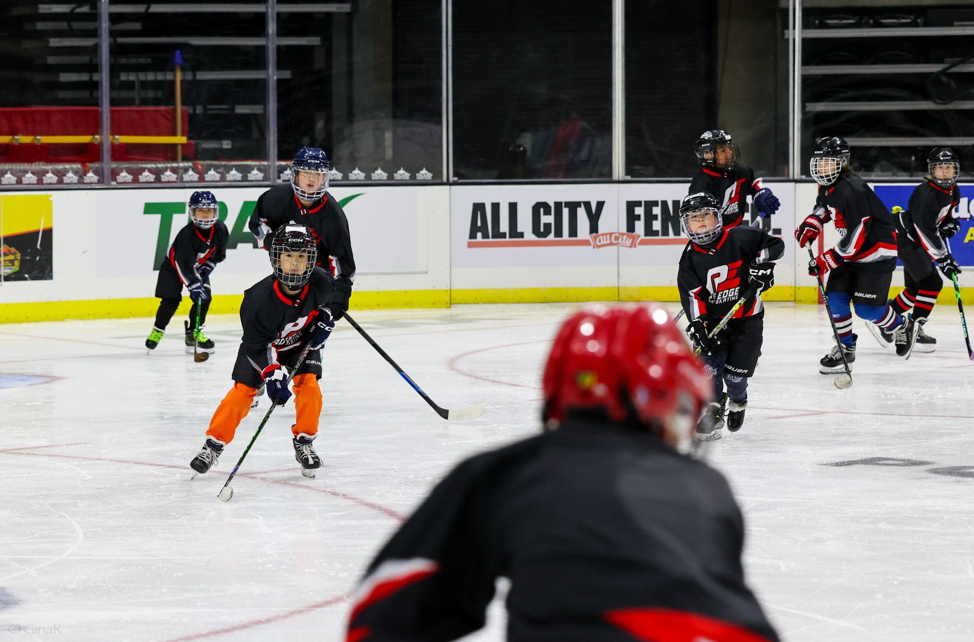 A hockey game is being played in front of an all city fence