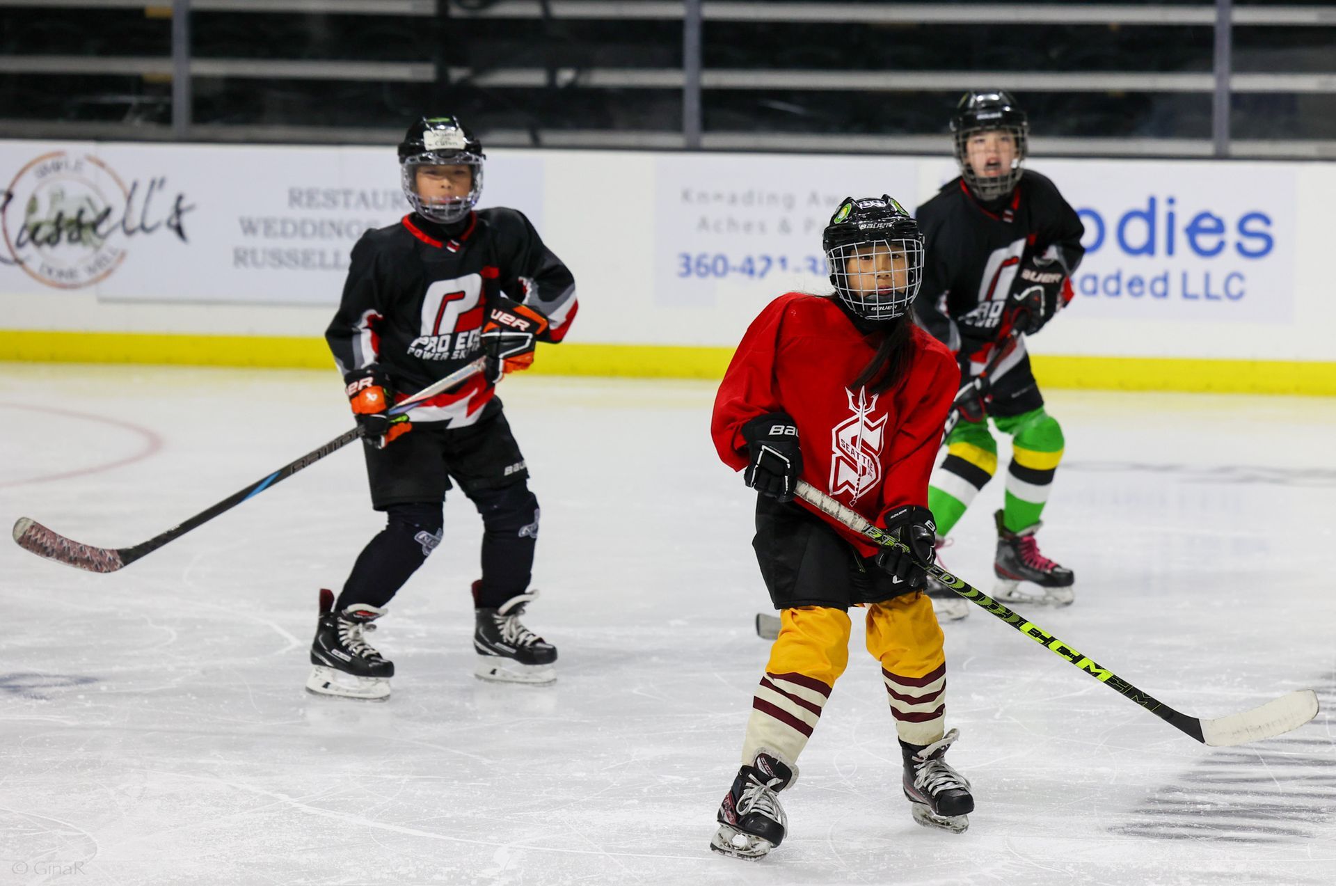 A group of young boys are playing ice hockey on a rink.
