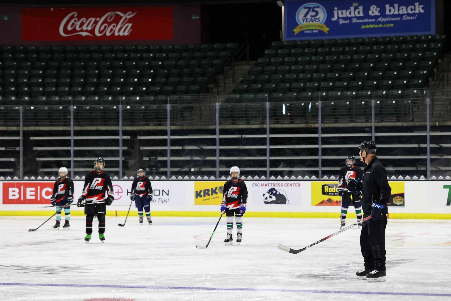 A group of hockey players are on the ice in front of a coca cola sign