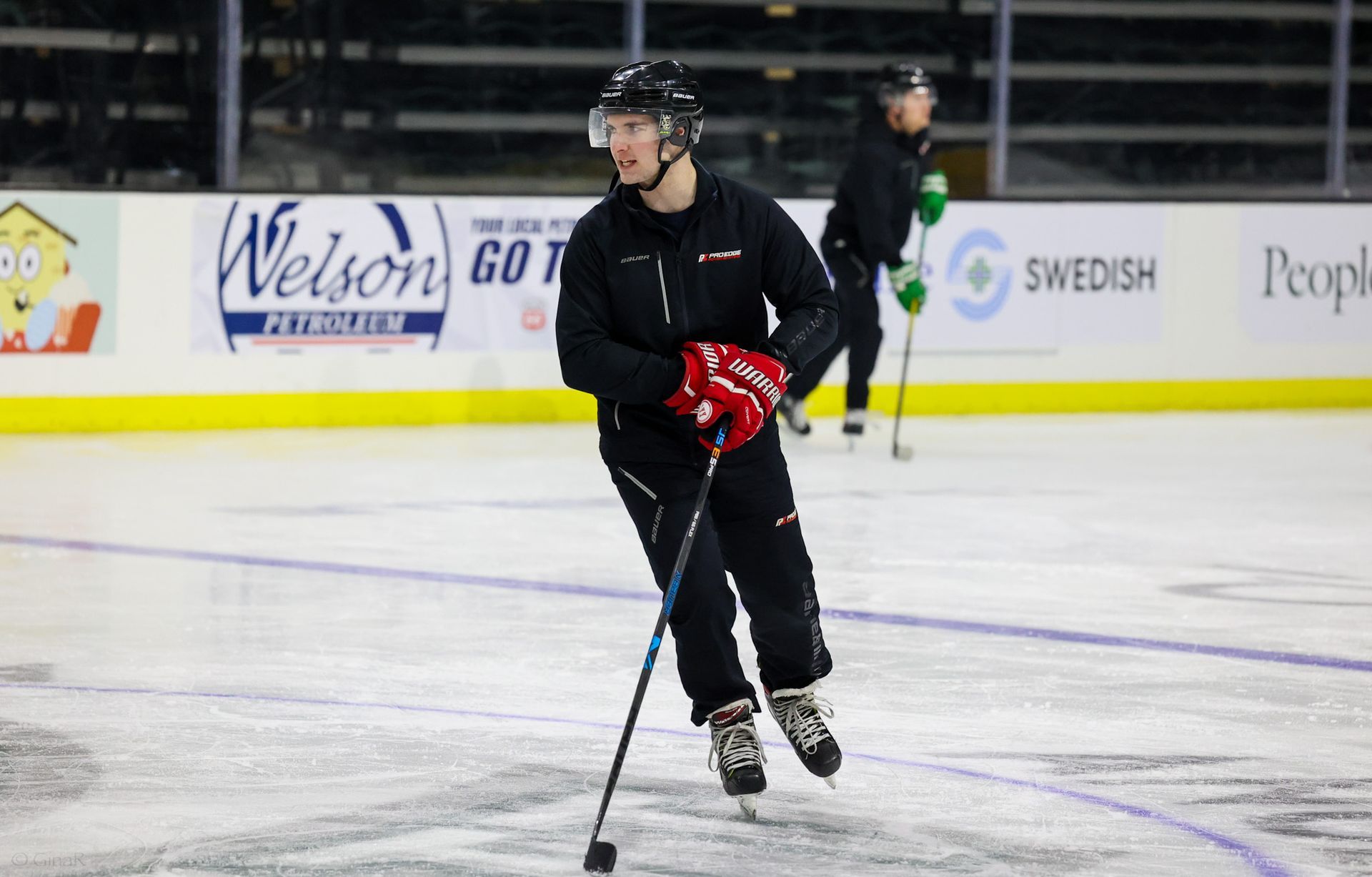 A man is holding a hockey stick on a rink.