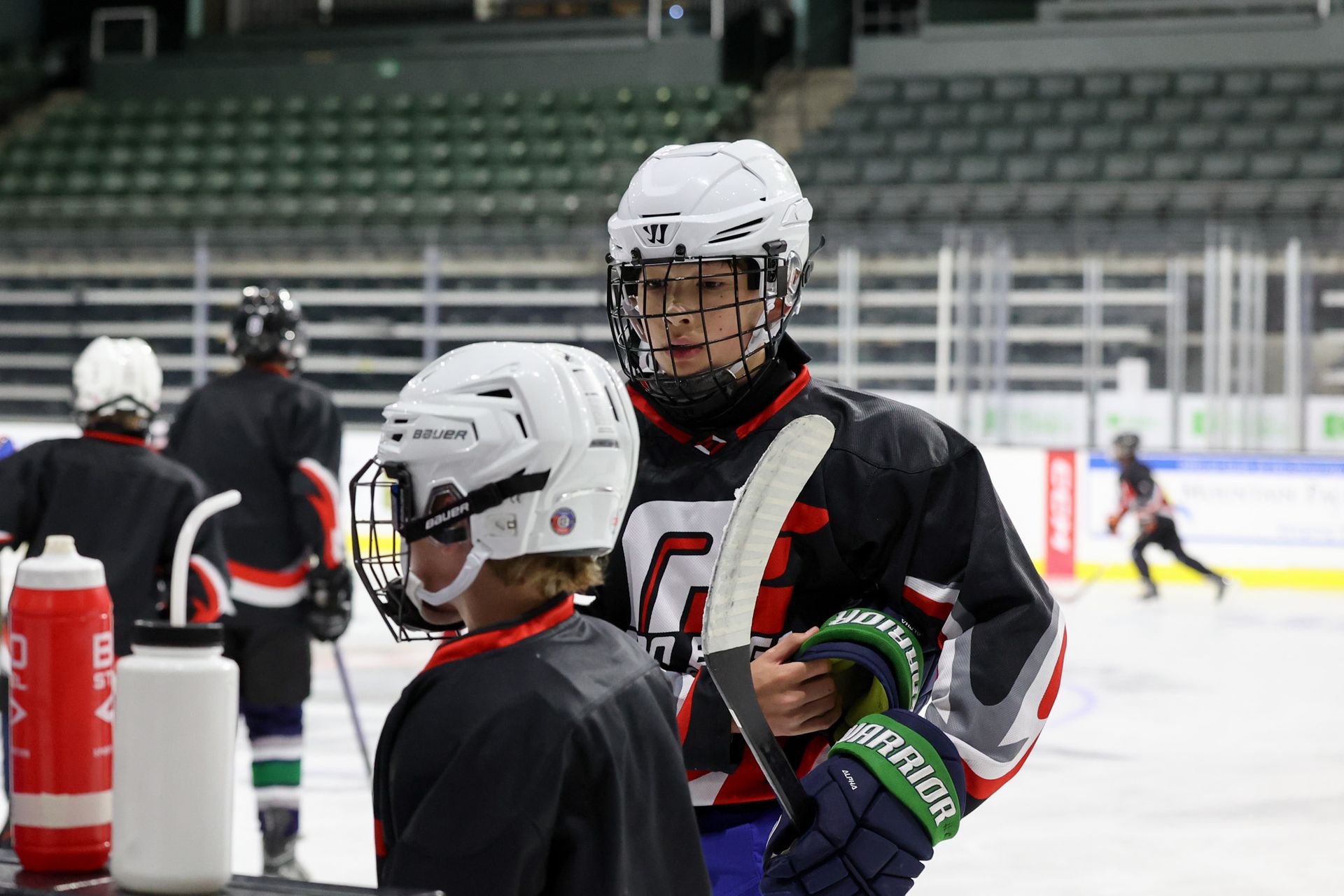 Two hockey players are standing on the ice talking to each other.