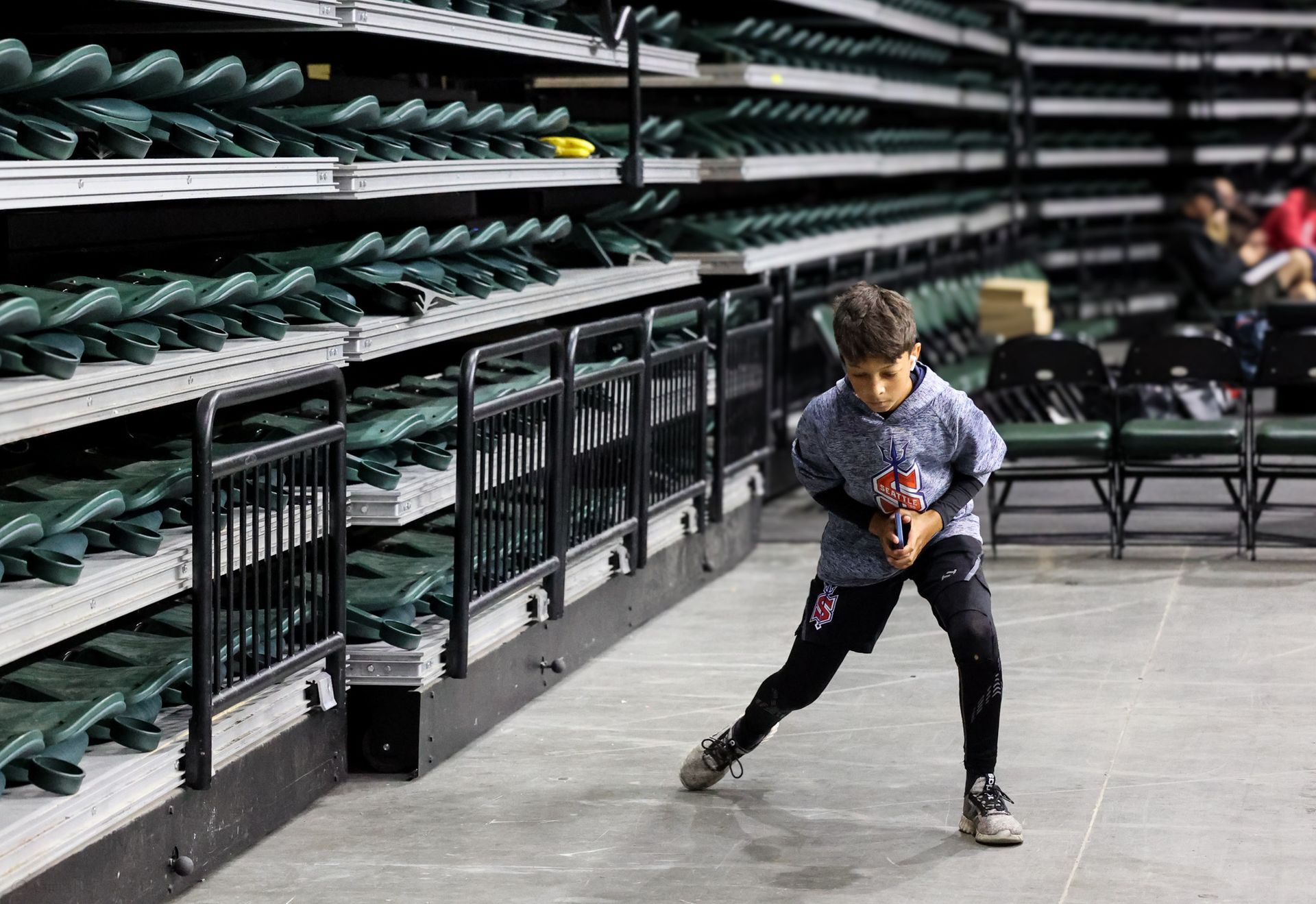 A young boy is practicing hockey moves in a stadium.