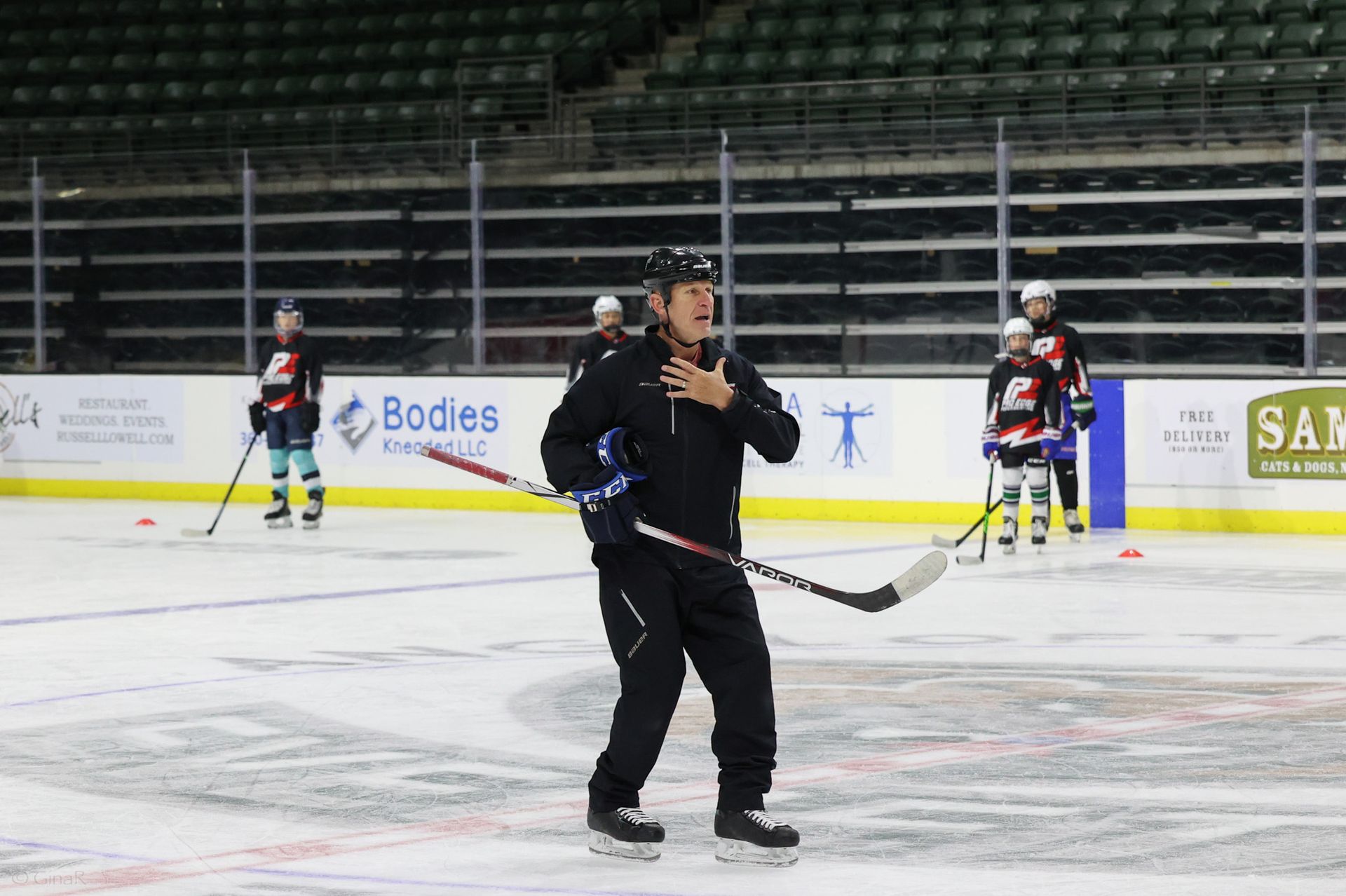 A man is holding a hockey stick on a ice rink.
