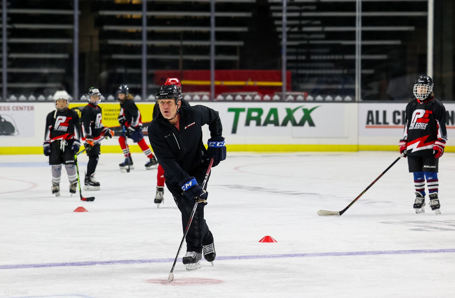 A group of hockey players are practicing on a rink sponsored by traxx.