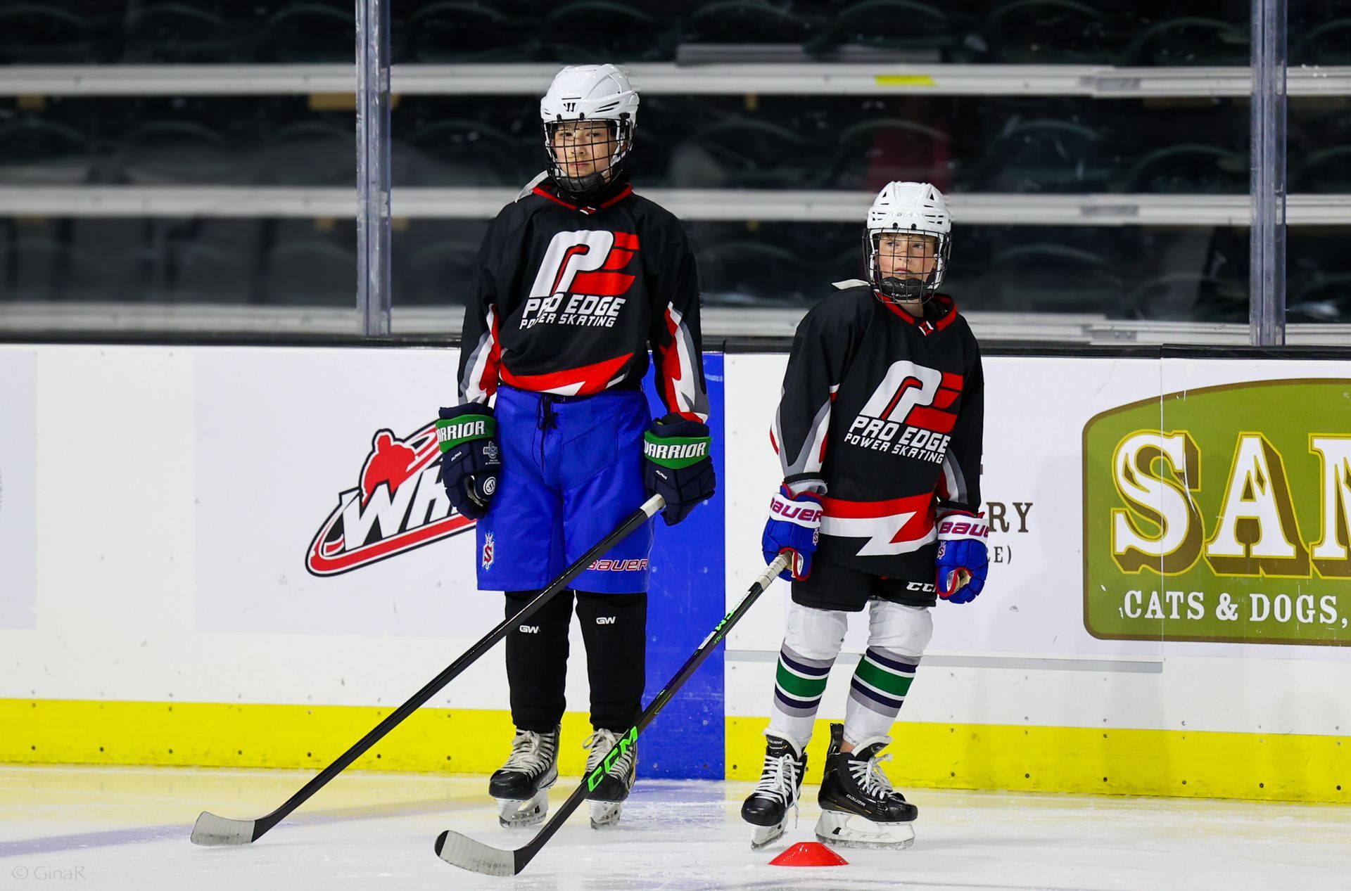 Two young hockey players are practicing on the ice.