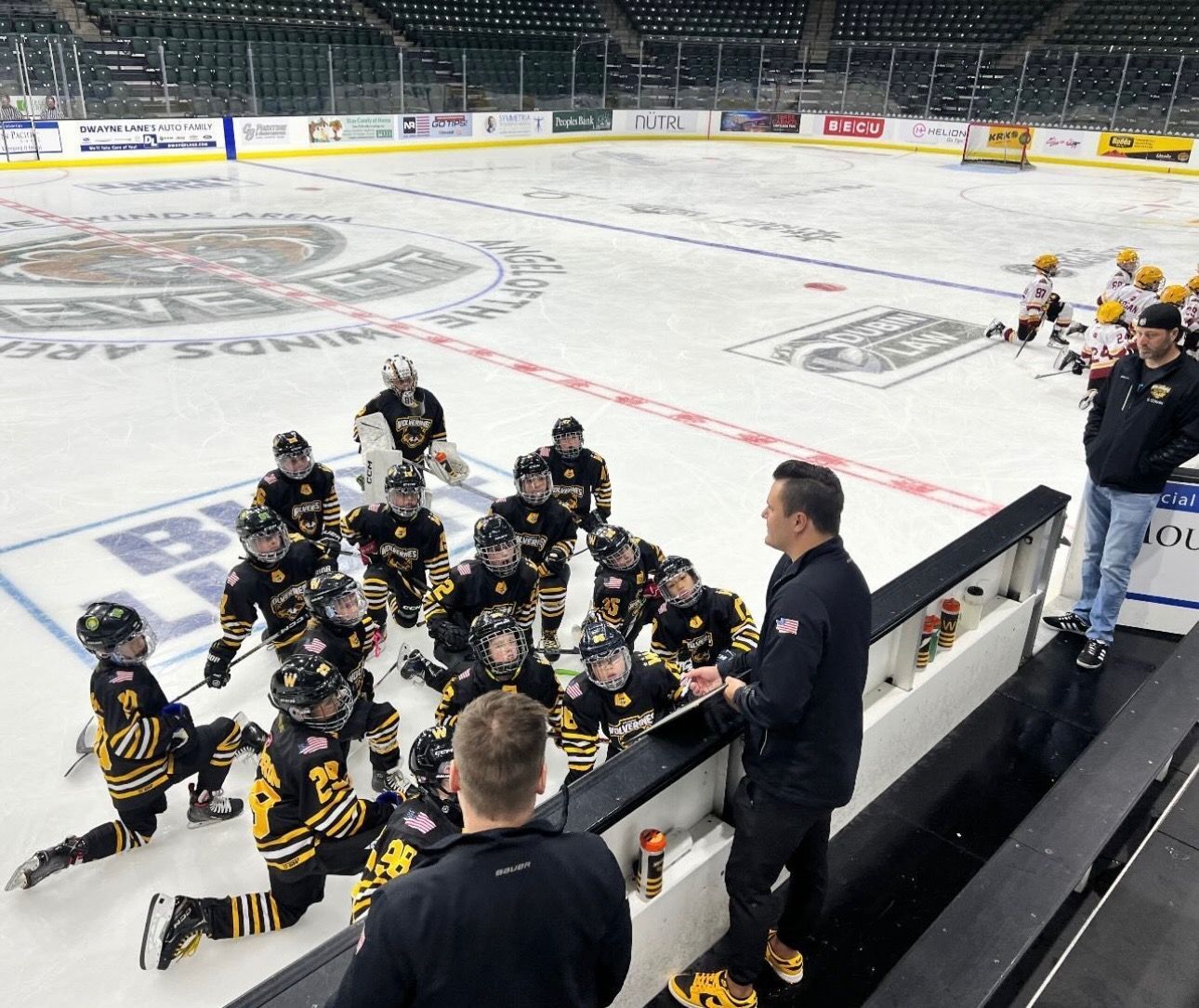 A group of hockey players are kneeling on the ice