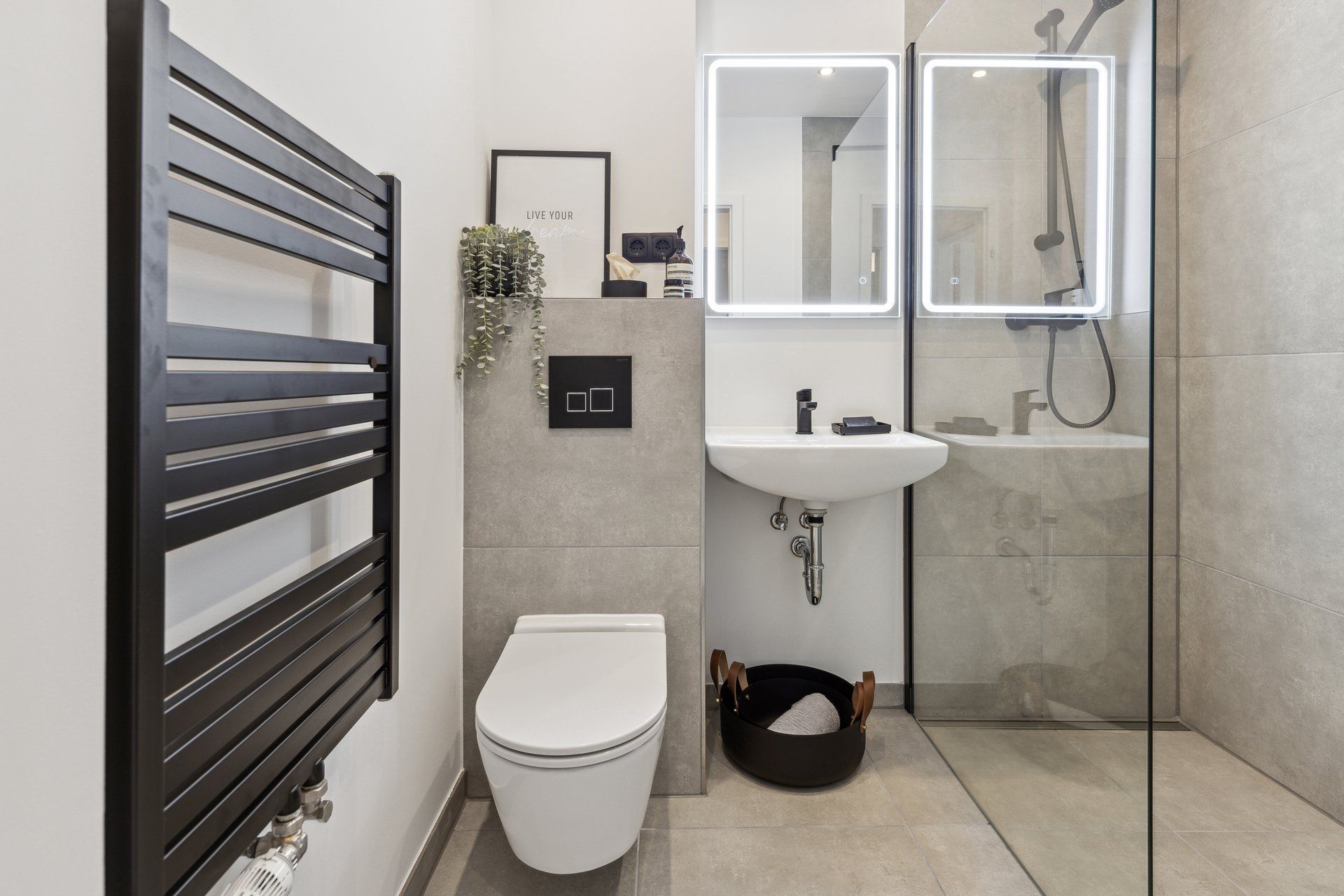 Ein Badezimmer mit Toilette, Waschbecken, Spiegel und ebenerdiger Dusche.