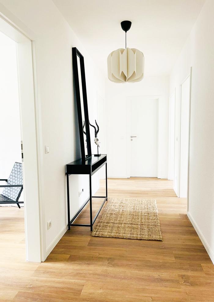 Ein langer Flur mit Holzboden und einem Spiegel an der Wand.