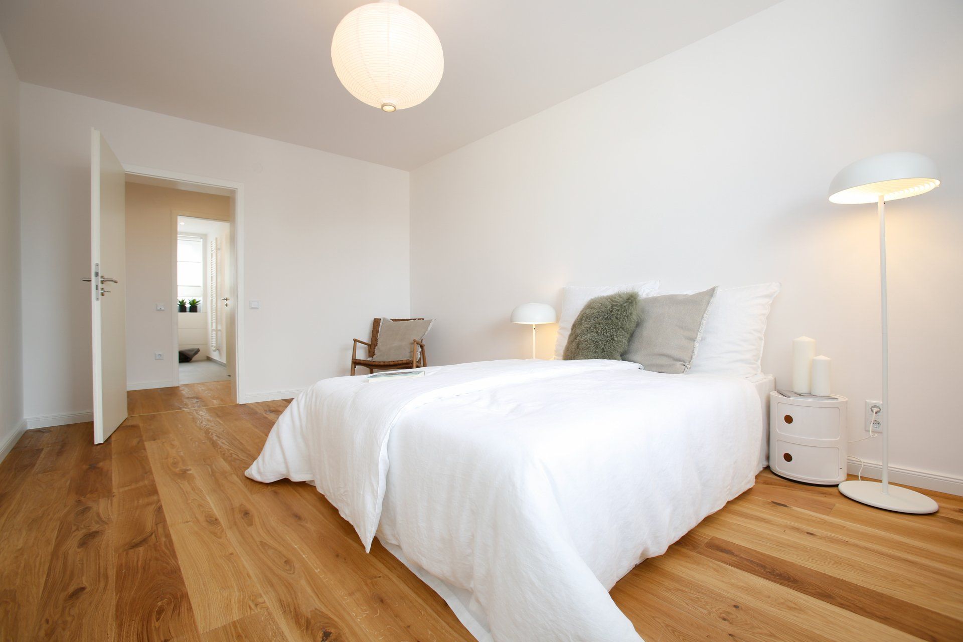 Ein Schlafzimmer mit Bett, Lampe, Nachttisch und Stuhl.